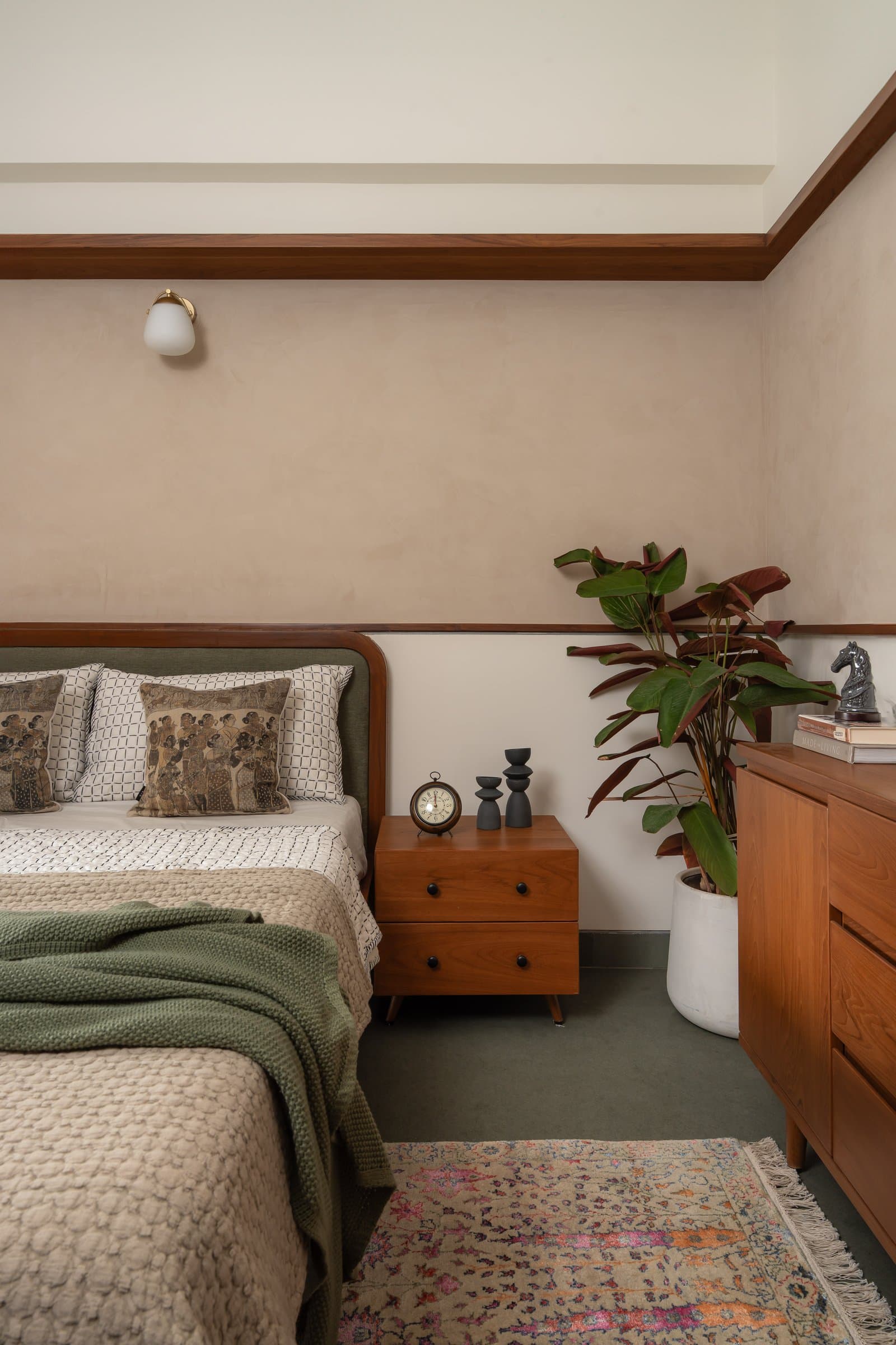 The guest bedroom, where forest green upholstery introduces the apartment's boldest chromatic note with complete assurance