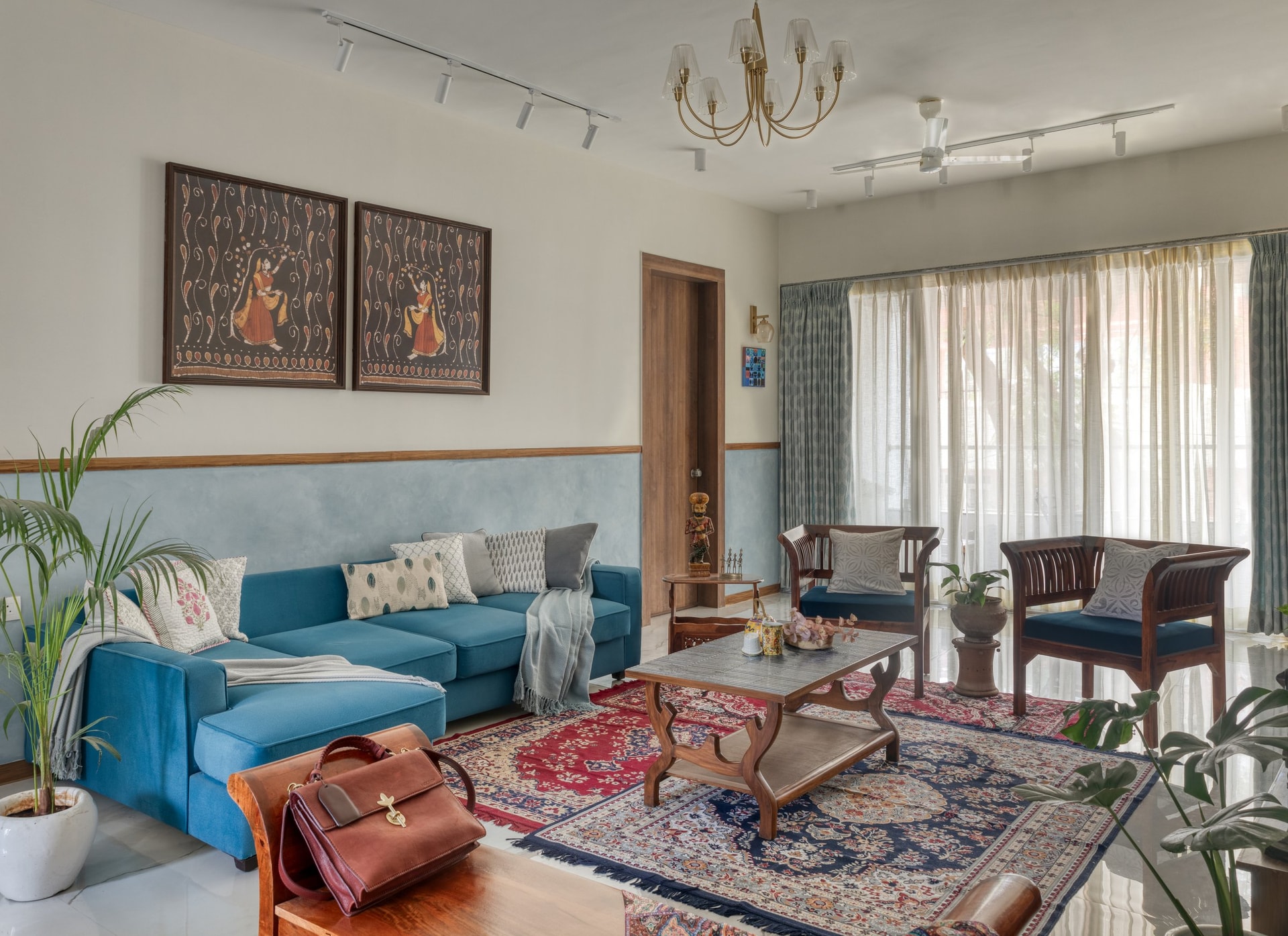 The living room, where a teal sectional and inherited timber furniture find common ground beneath traditional paintings
