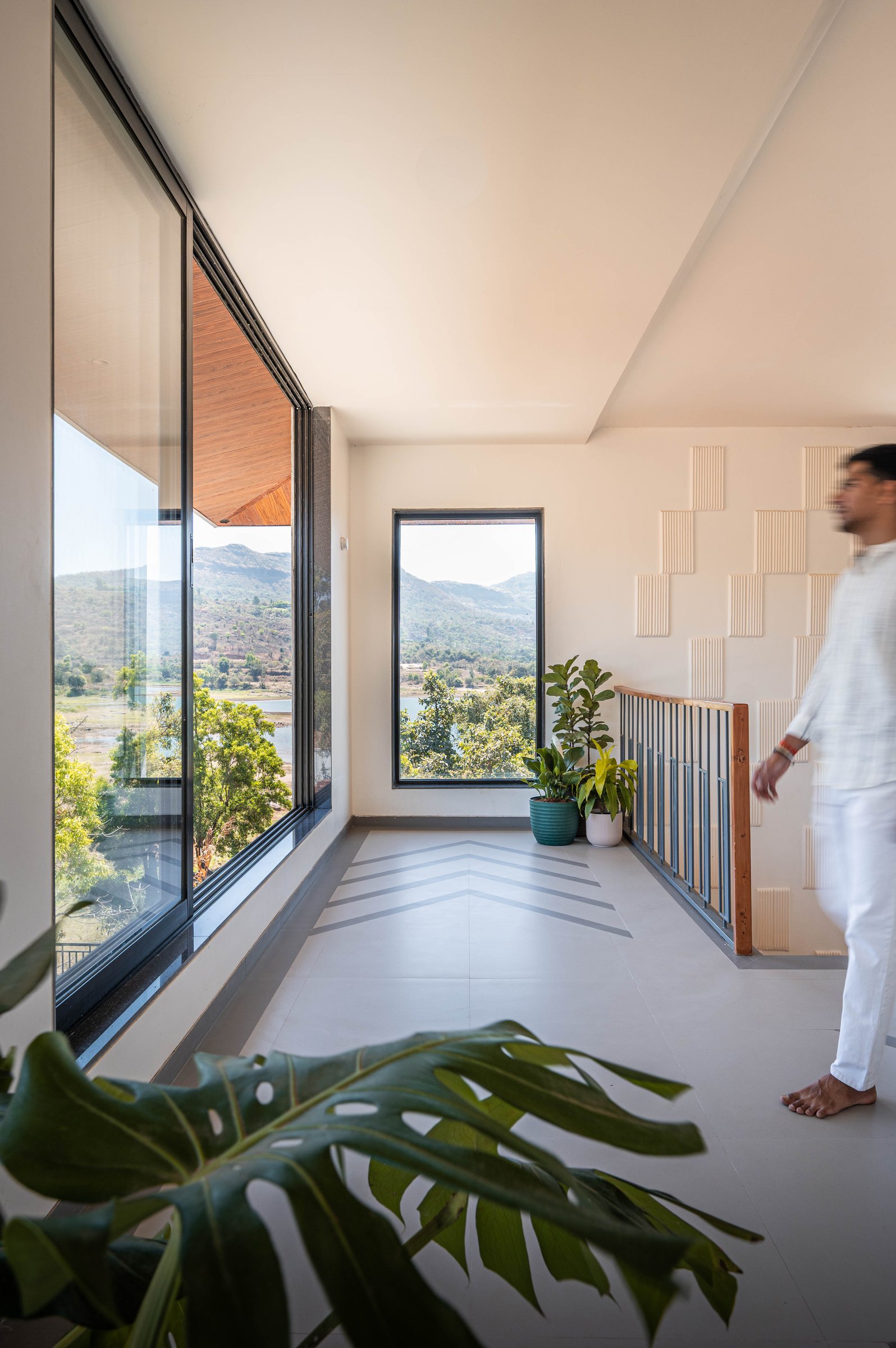 The stair landing, where corner-meeting glass opens to an unbroken panorama of hills and water