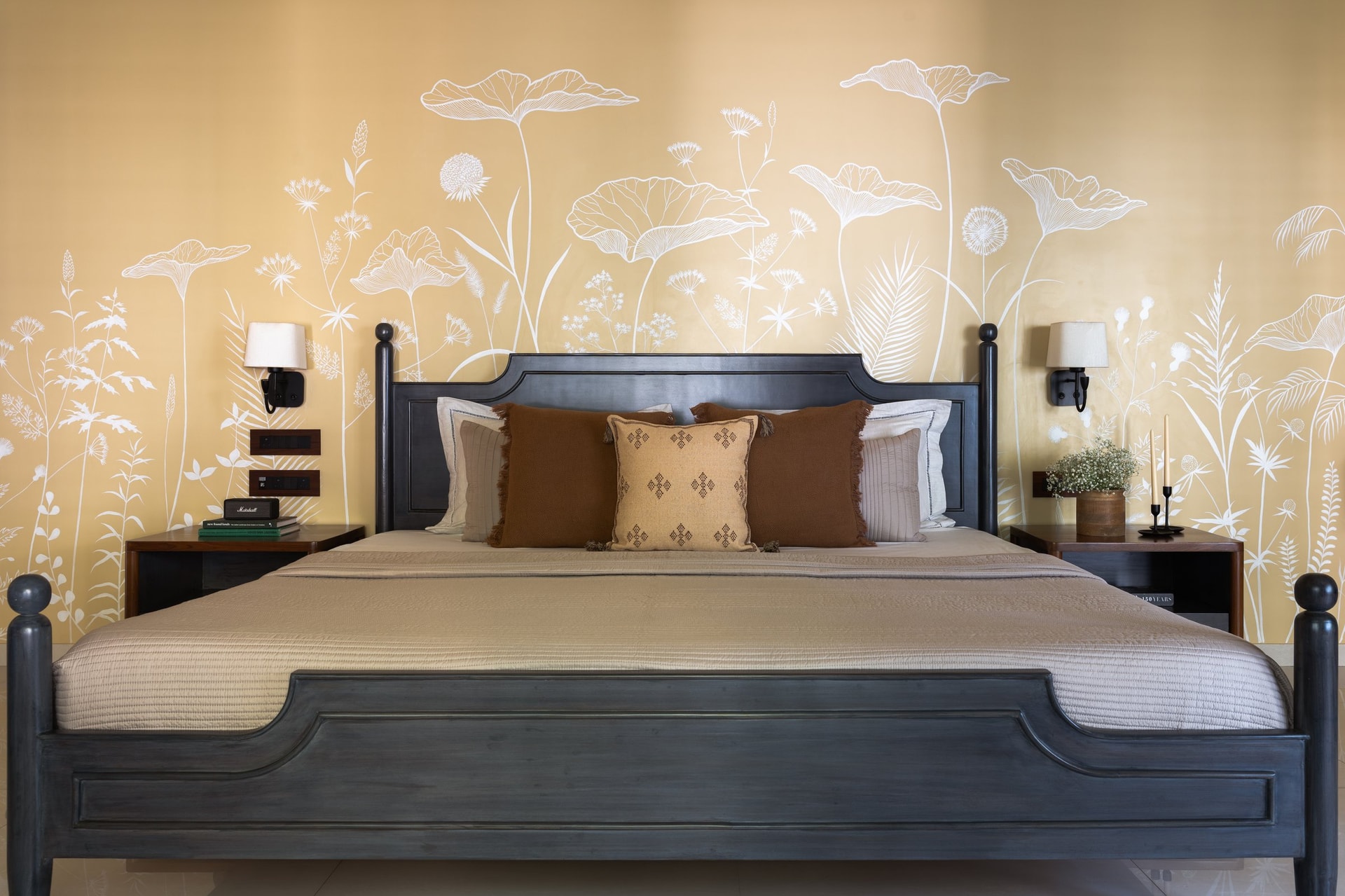 A hand-painted botanical mural in warm gold wraps the second bedroom's headboard wall