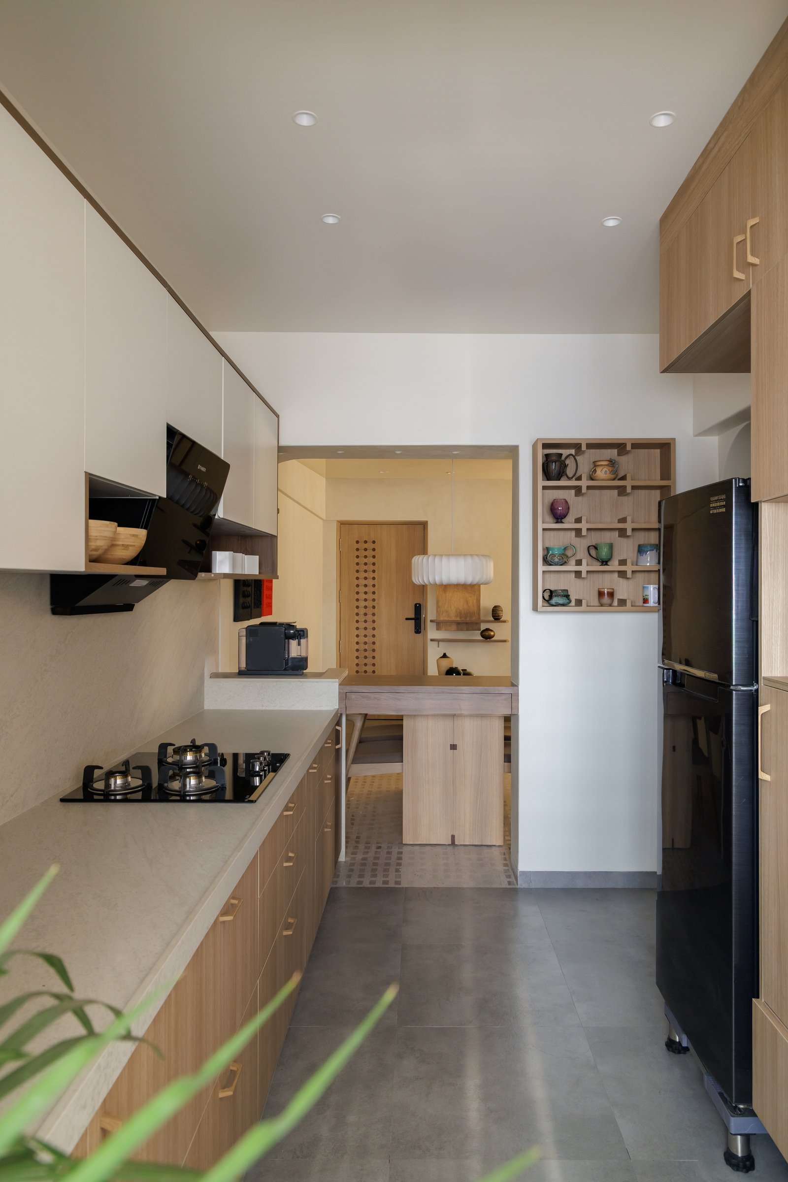 The galley kitchen, its corridor terminating at the perforated entry door in a quiet interior axis