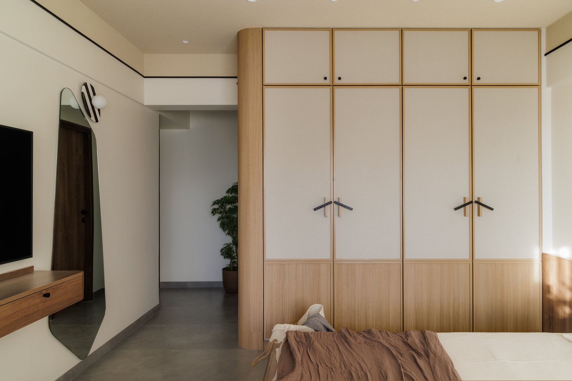 The dressing zone, with an irregular leaning mirror and a slim walnut console