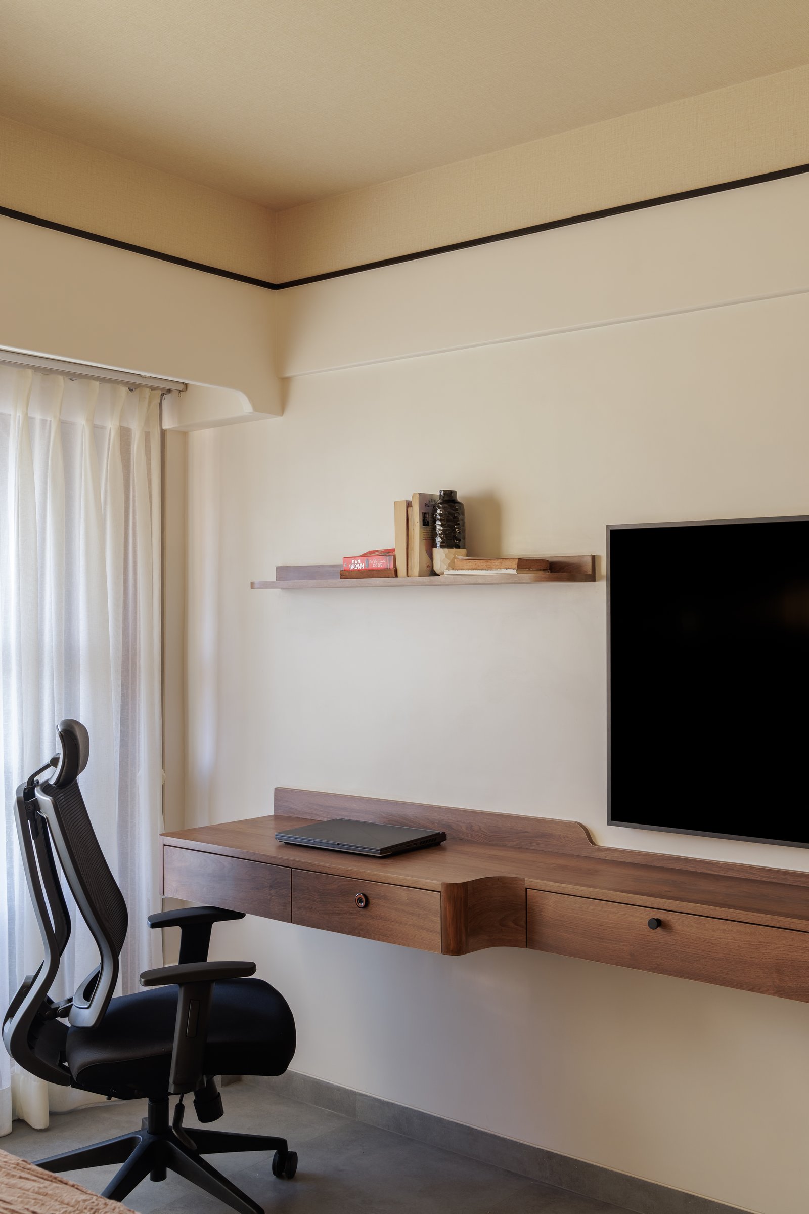 A study niche tucked into the bedroom: a stepped walnut desk under a floating shelf