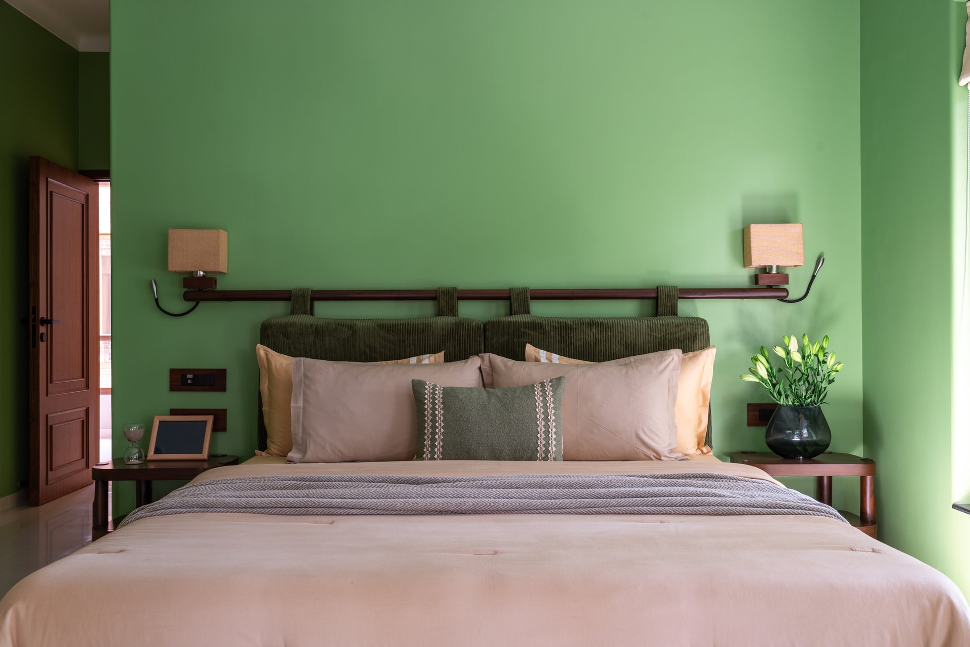 The guest bedroom's sage green walls and corduroy-cushioned headboard create an enveloping tonal departure
