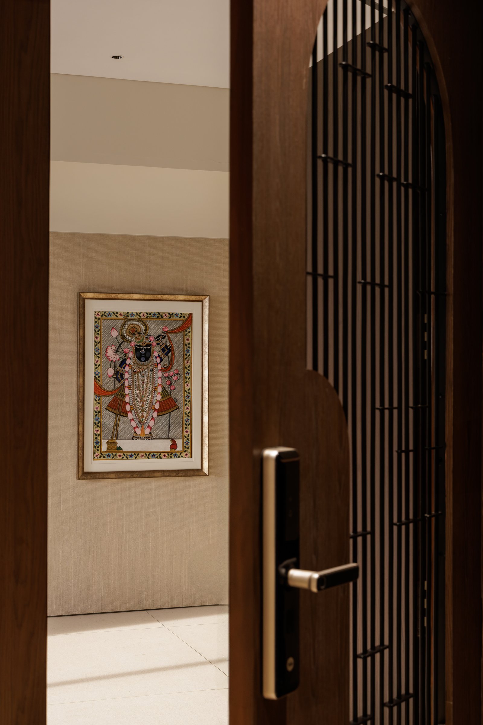 The inner foyer reveals its first reward, a framed Shrinathji pichhwai against a softly textured wall