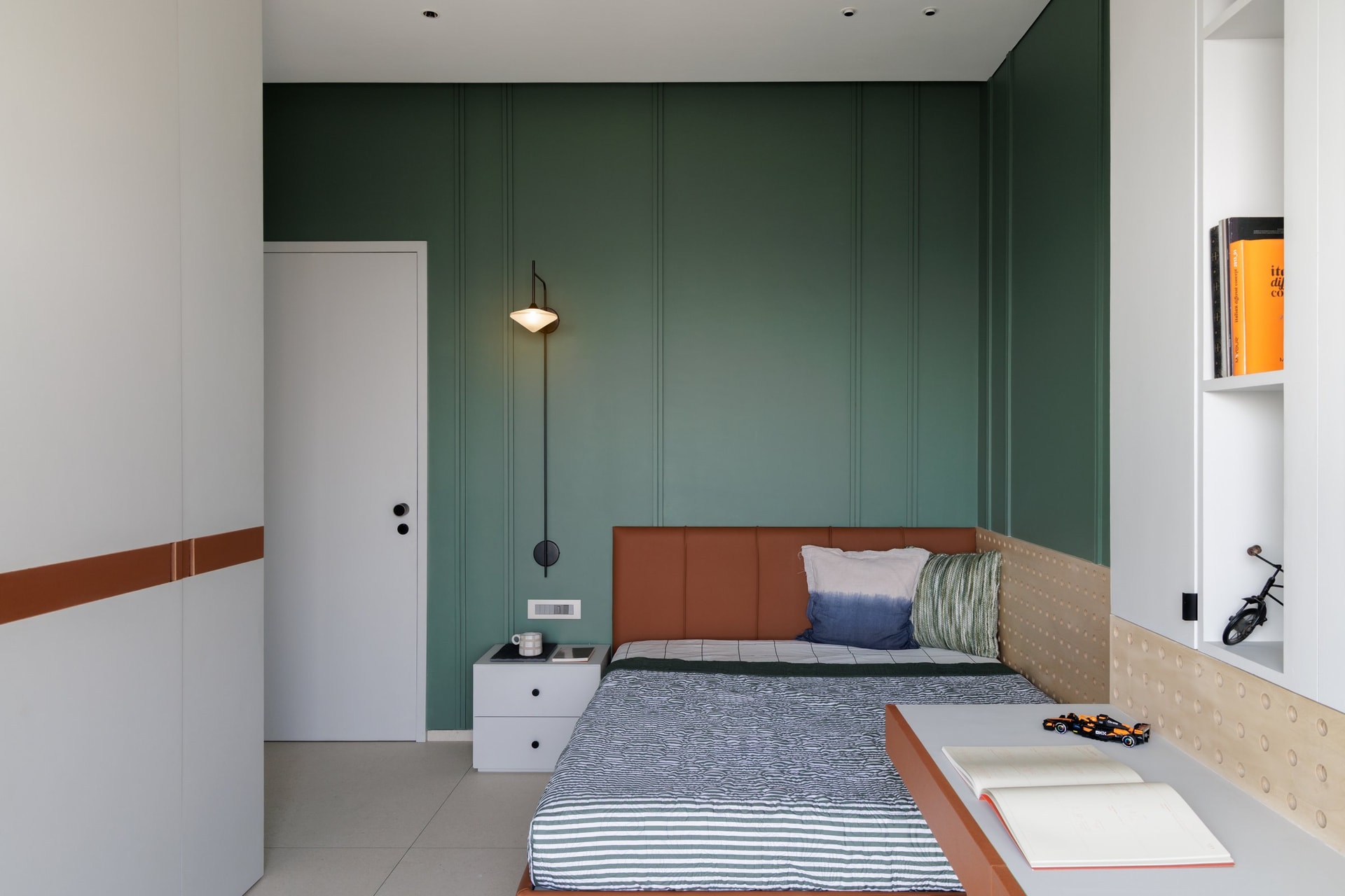 The son's bedroom, where a forest green panelled wall and a tan leather headboard set the room's graphic register
