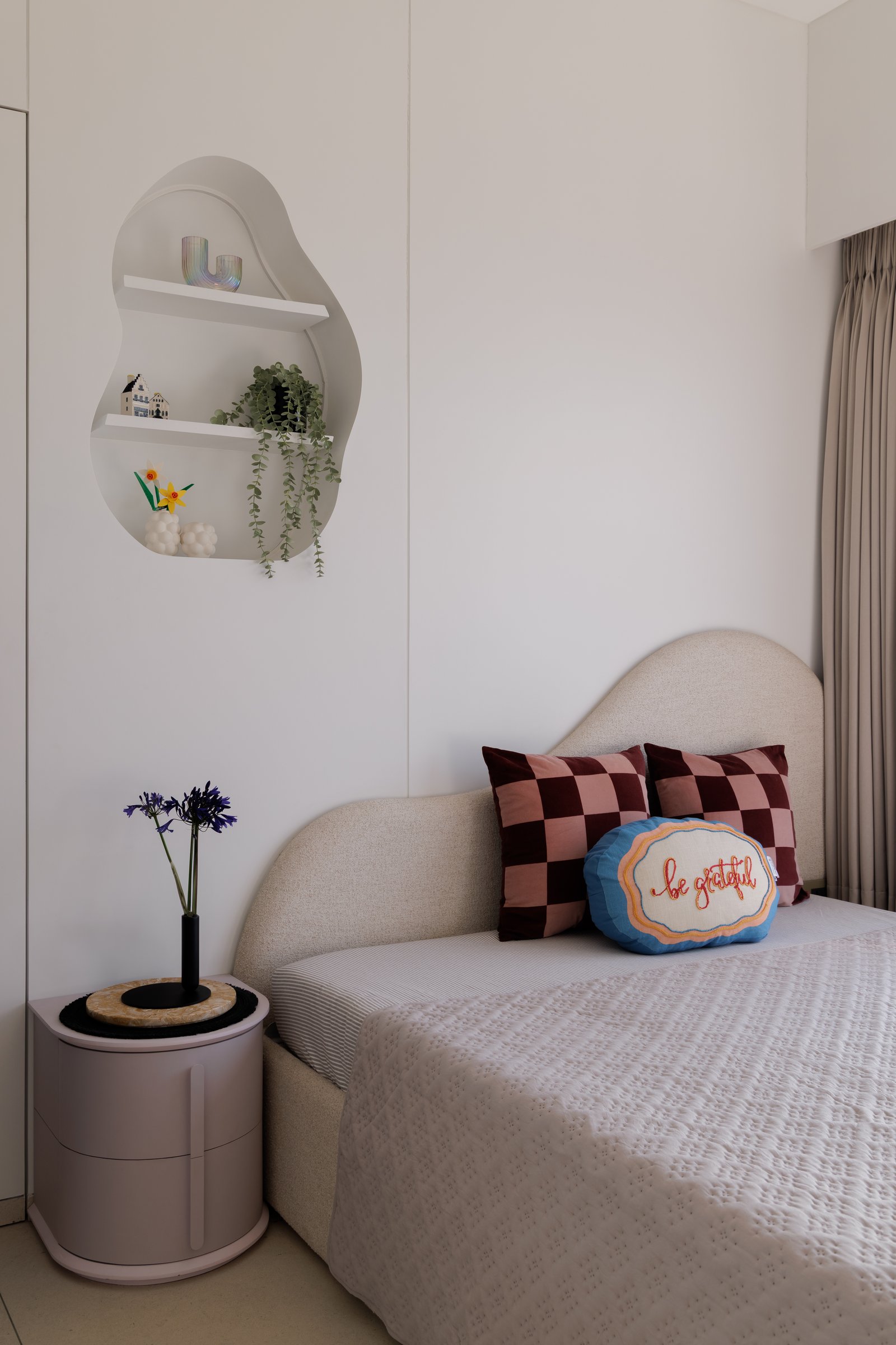 The daughter's bedroom: a curved oatmeal headboard, a pebble-shaped shelf, and one playful gesture per wall