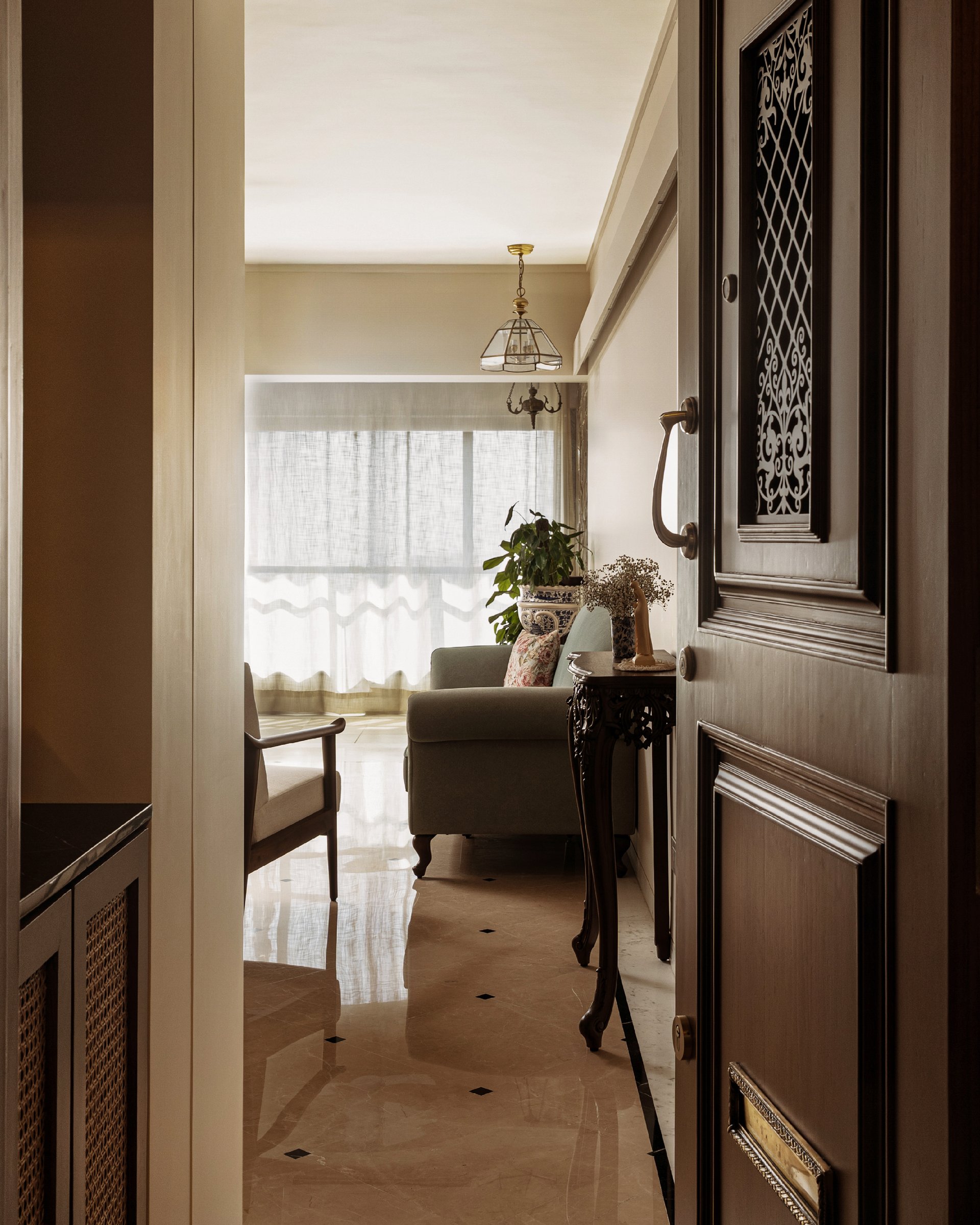 The entry view into the living room, where a wrought-iron door grille and diamond-inlaid marble floor set the home's vintage register