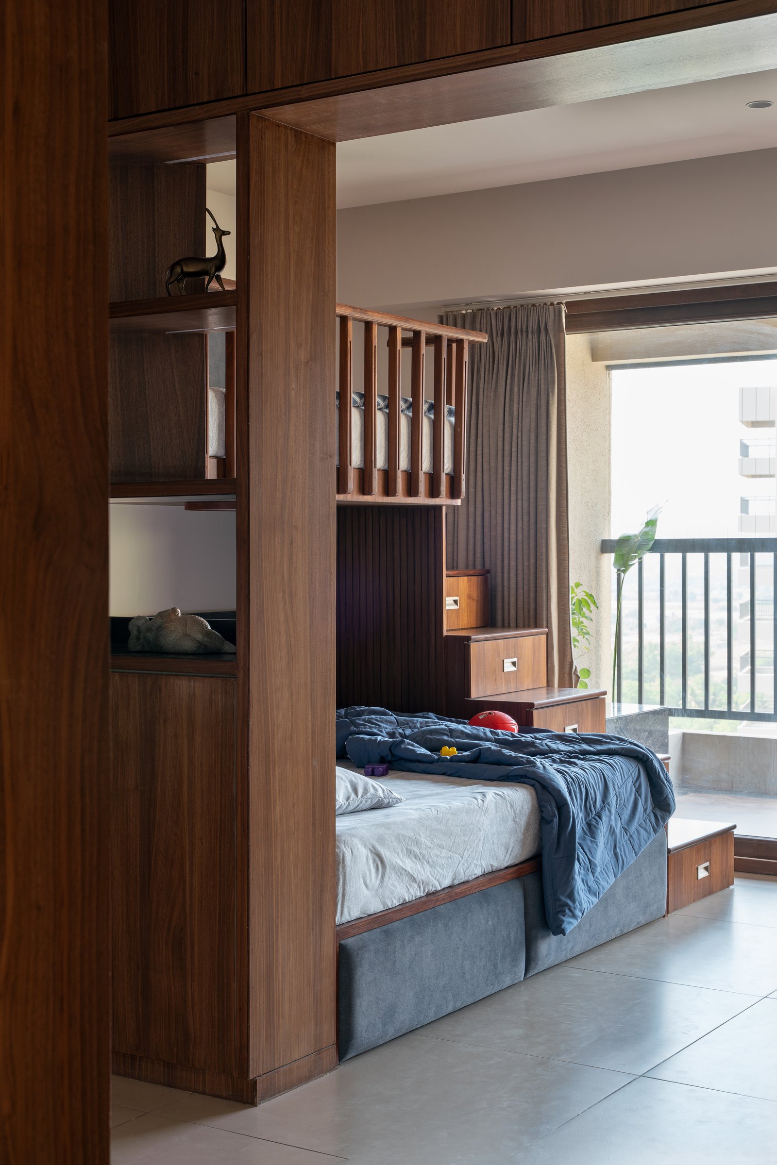 The children's room compresses bunk beds, play zone, and storage into one walnut-framed volume