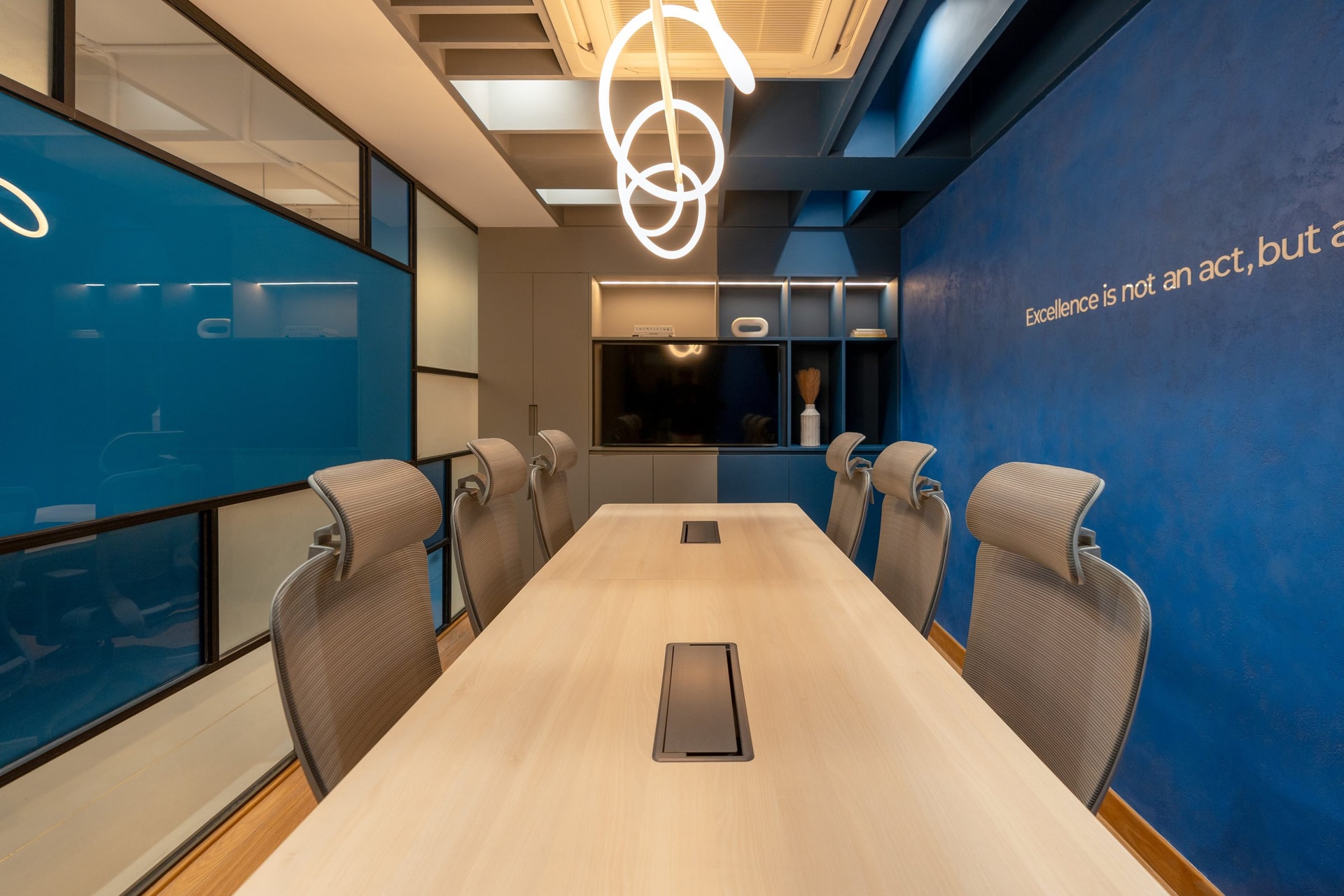 The conference room, where a single sculptural ring pendant earns its flourish against otherwise straight geometries
