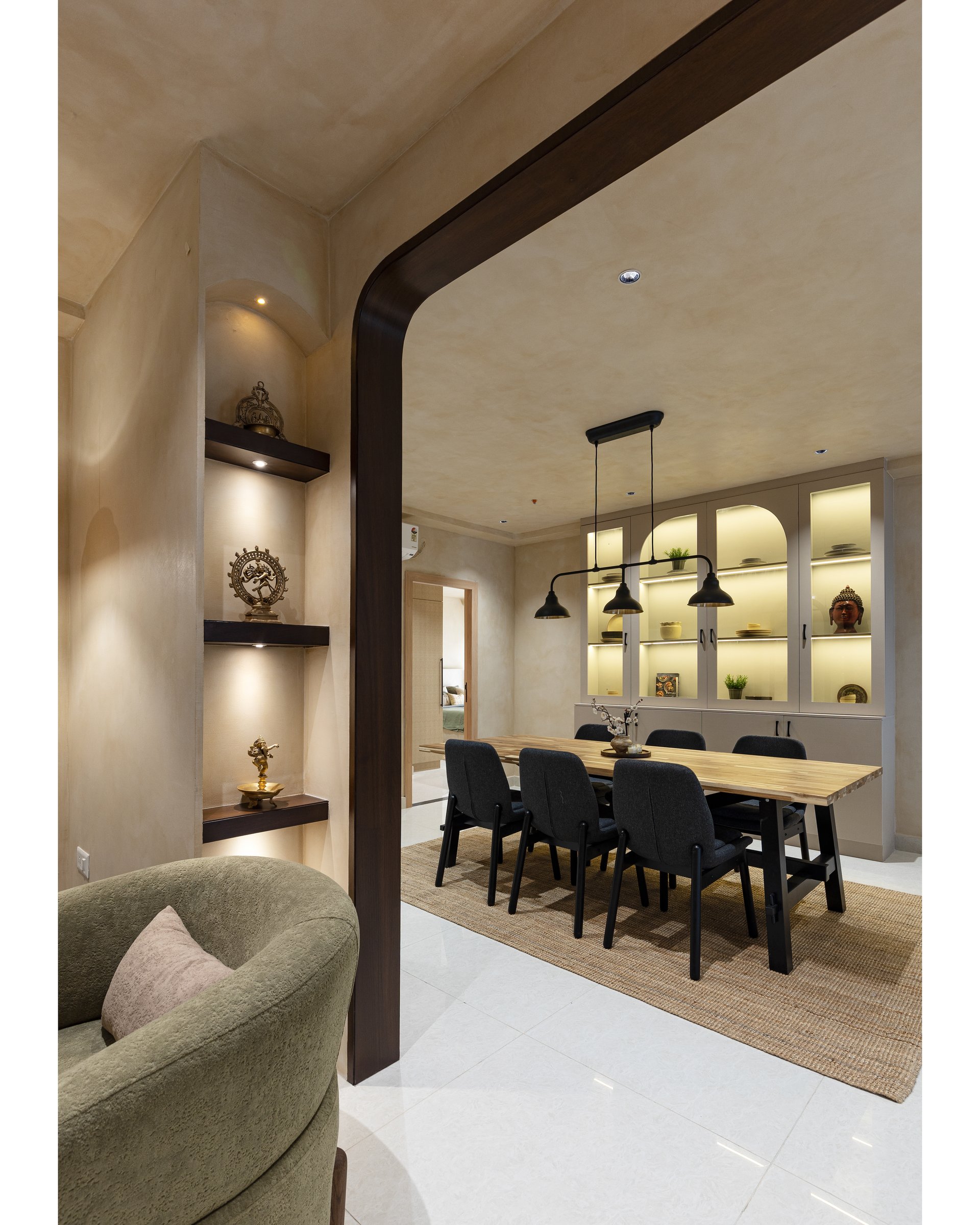 The dining side of the puja partition, with a brass-and-Nataraja niche mirrored by a glass-fronted display cabinet
