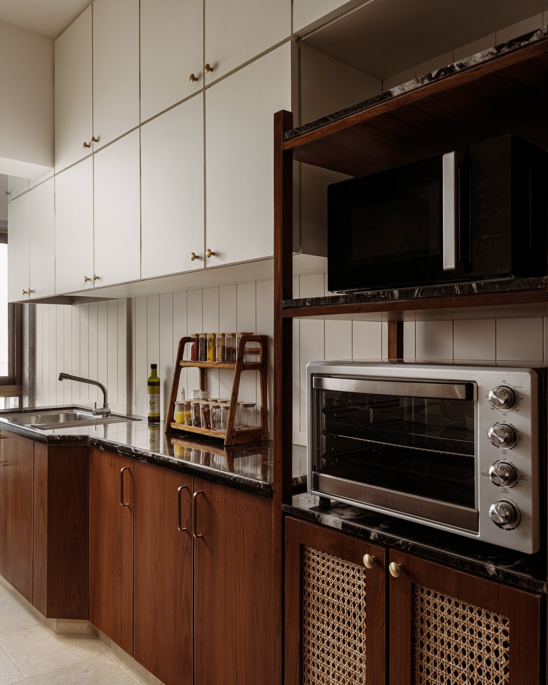 Inside the kitchen, cane-fronted cabinet doors below the appliance shelf are the apartment's most quietly contemporary gesture