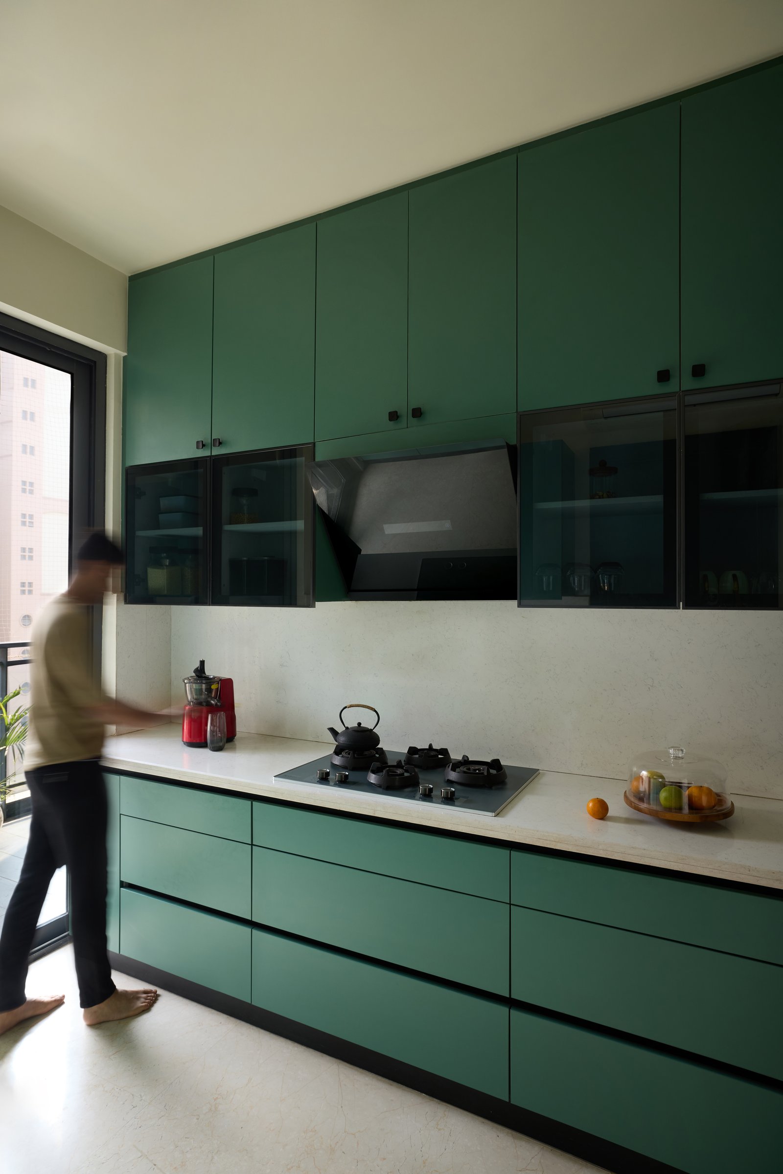 The kitchen, where deep green cabinetry runs floor to ceiling against a pale stone counter
