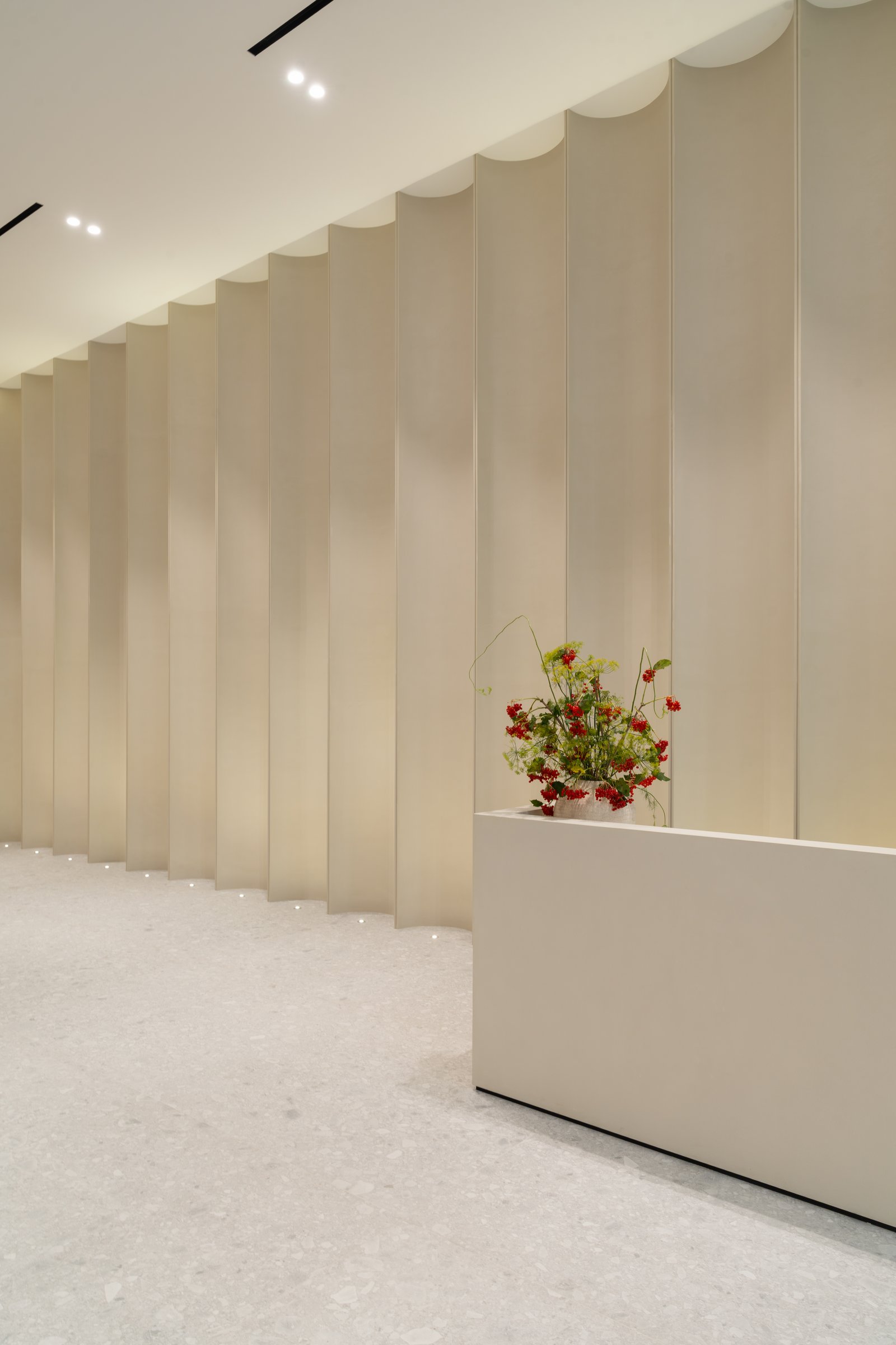 The arrival corridor: GRC concave panels and Ceppo di Gré flooring give the entrance the measured rhythm of a cloister
