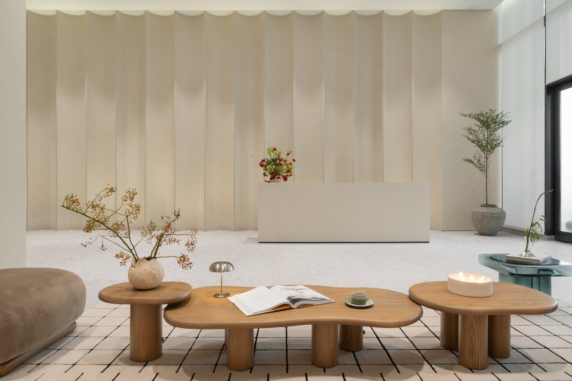 A floating reception desk against the panelled wall, with a weathered ceramic urn introducing the project's one overtly handcrafted note