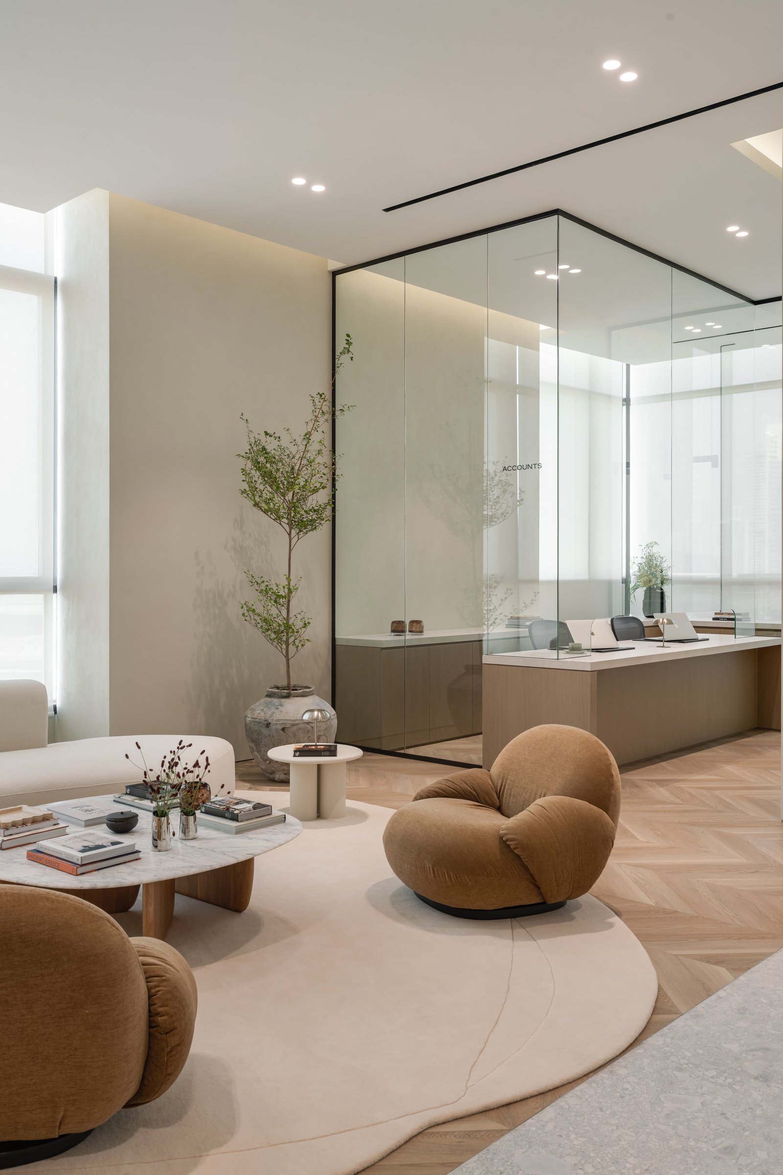 Beyond the lounge cluster, the glass-walled accounts office holds the same finish discipline as the public zones