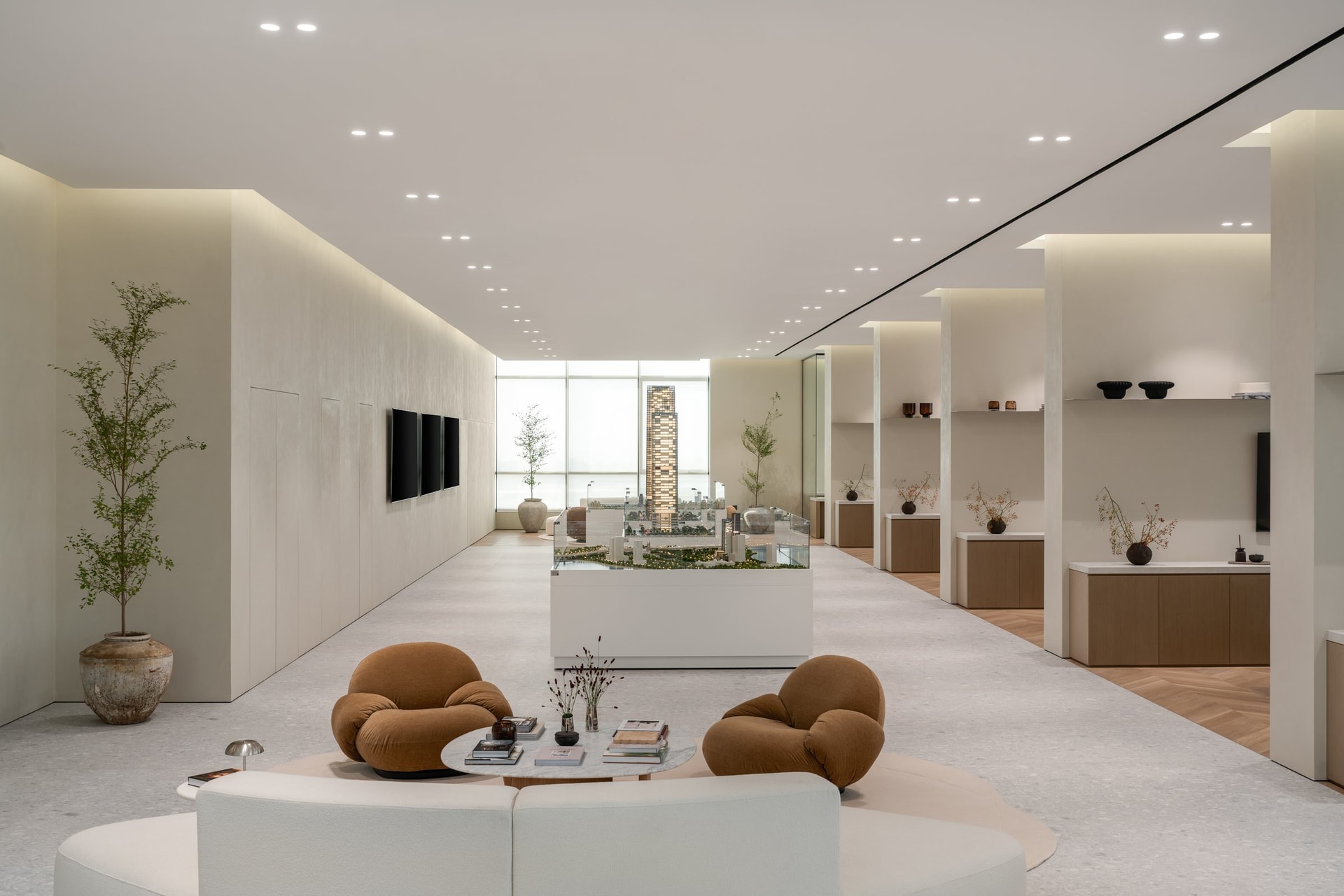 The central sales floor: a glass-enclosed model display anchors a long, gallery-like aisle of pale oak plinths
