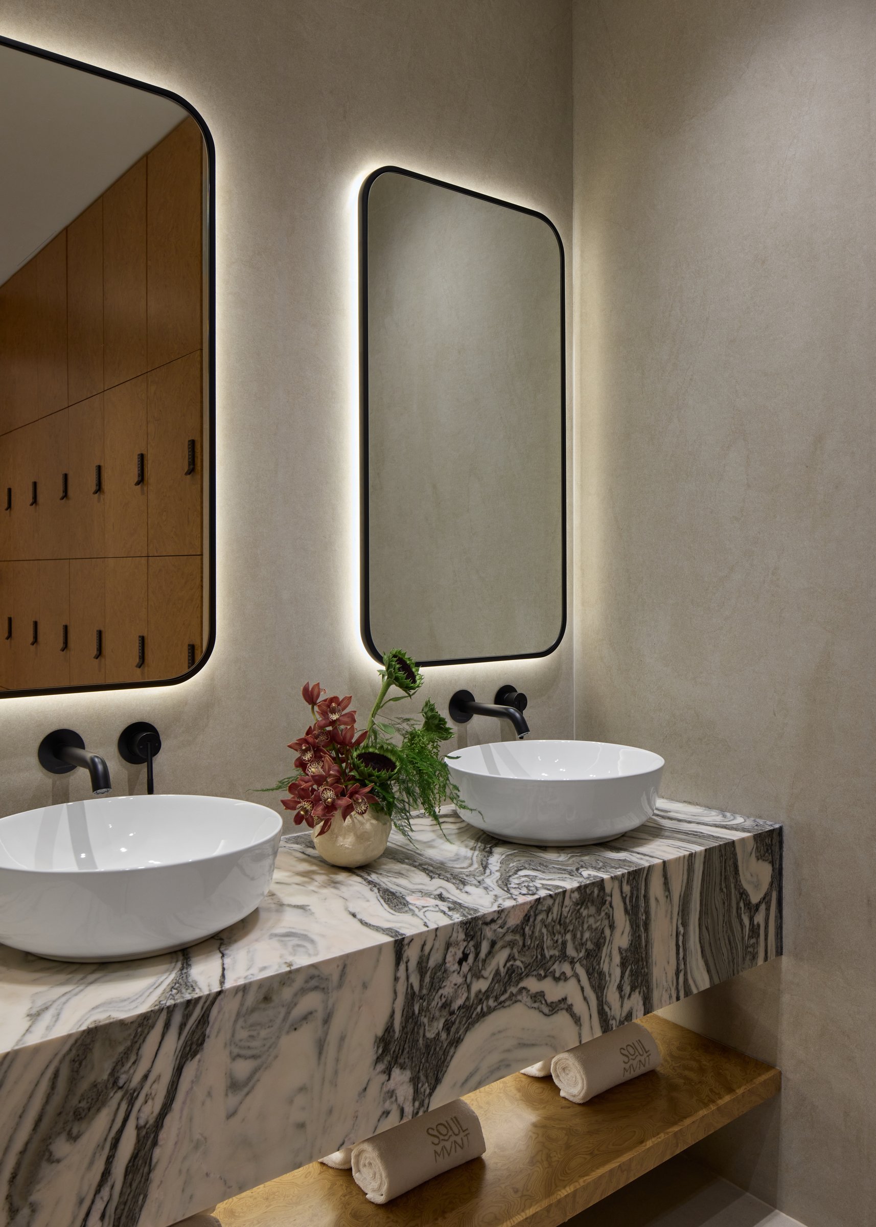 Vanity detail in Avalanche marble, with backlit rounded-corner mirrors and matte black taps