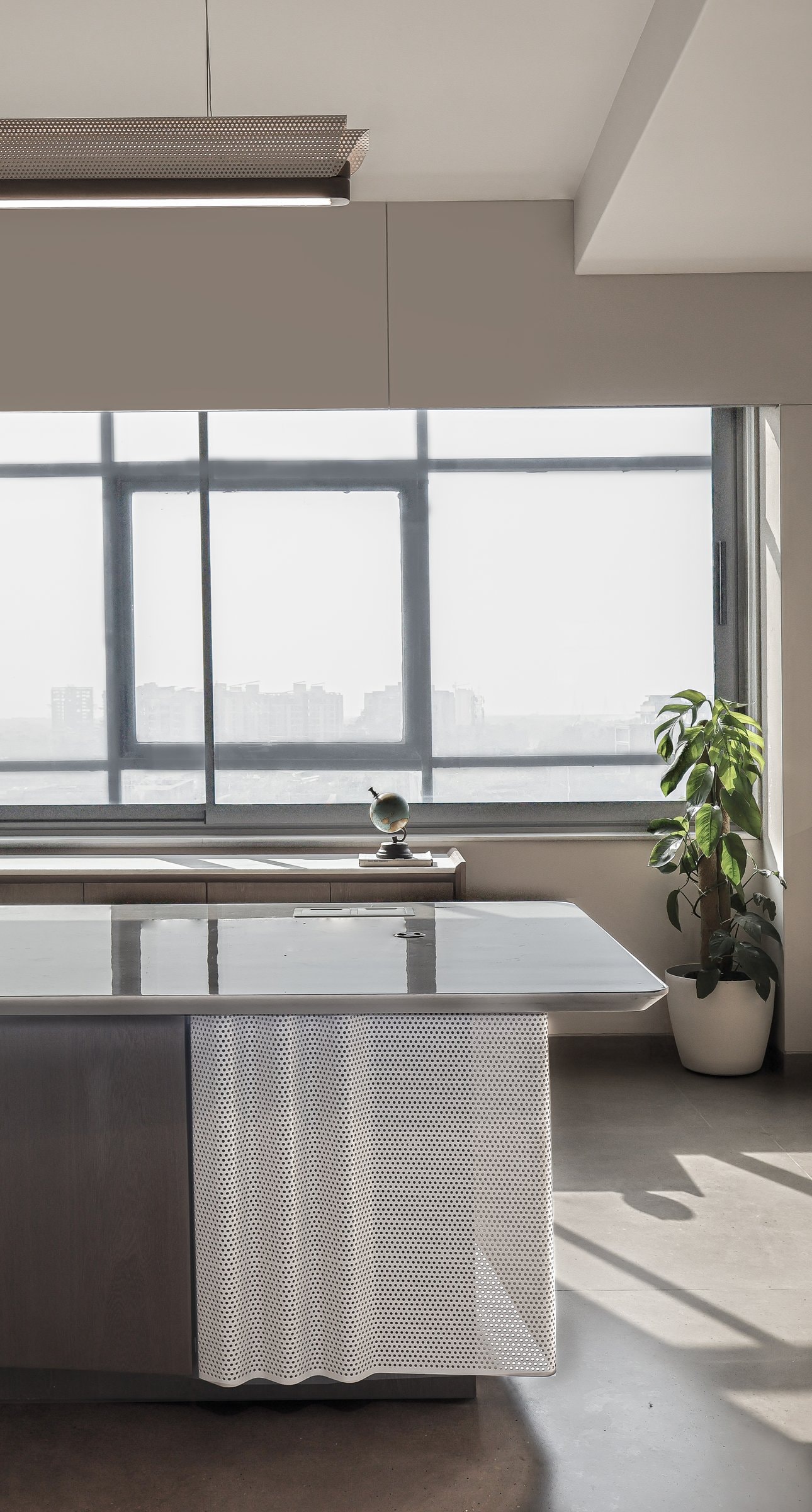 The cabin desk surface in close view: stone top, perforated metal apron, a globe anchoring the scale