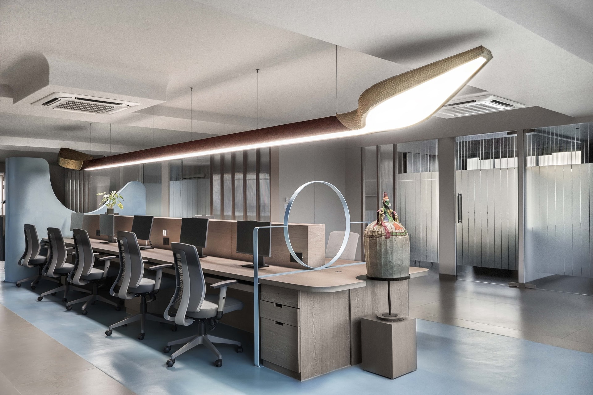 The same workstation island from the opposite end, where the painted curve dissolves into glass partitions