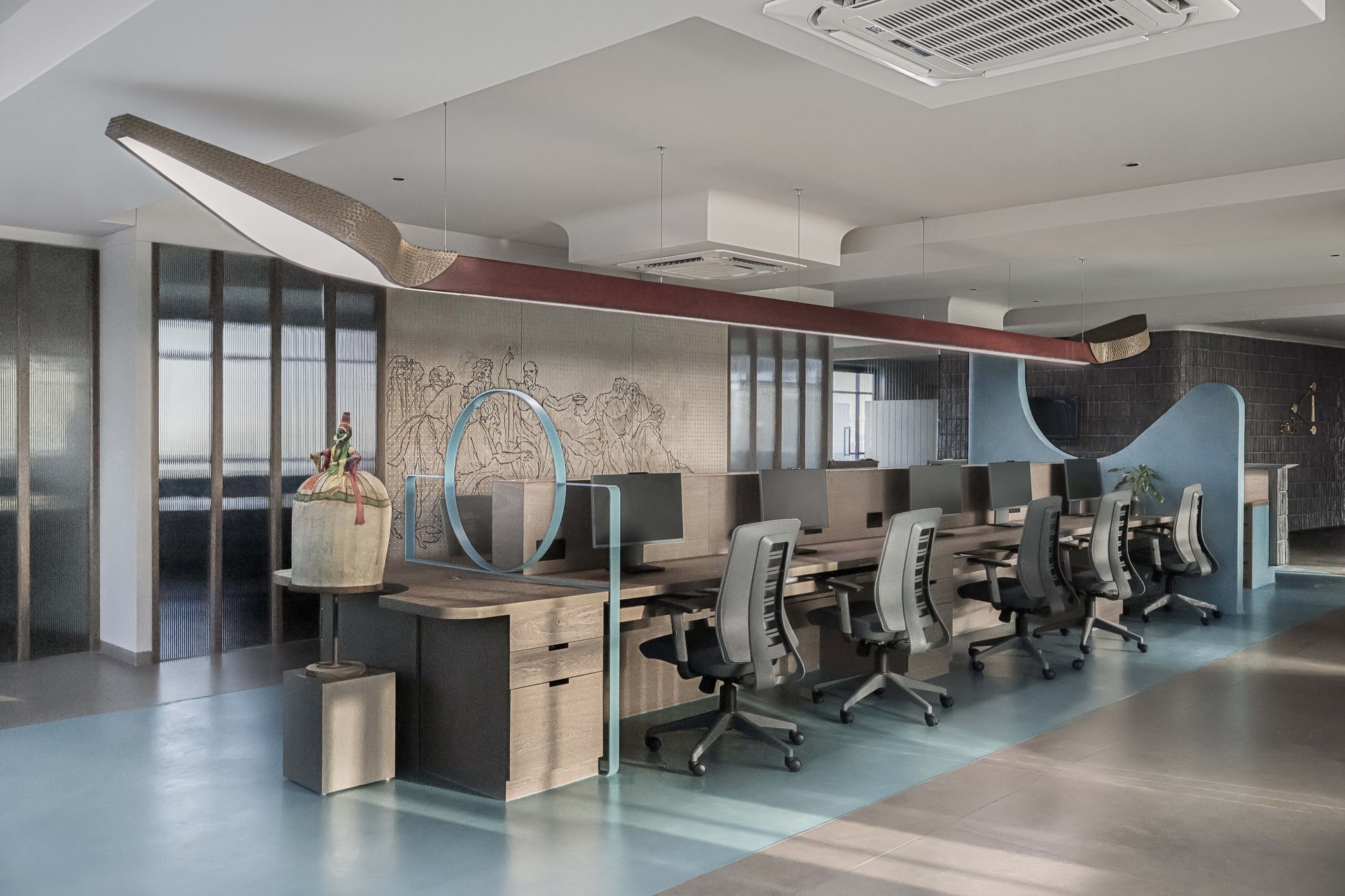 The central workstation bay, anchored by the bespoke red pendant and a folk figurine pedestal