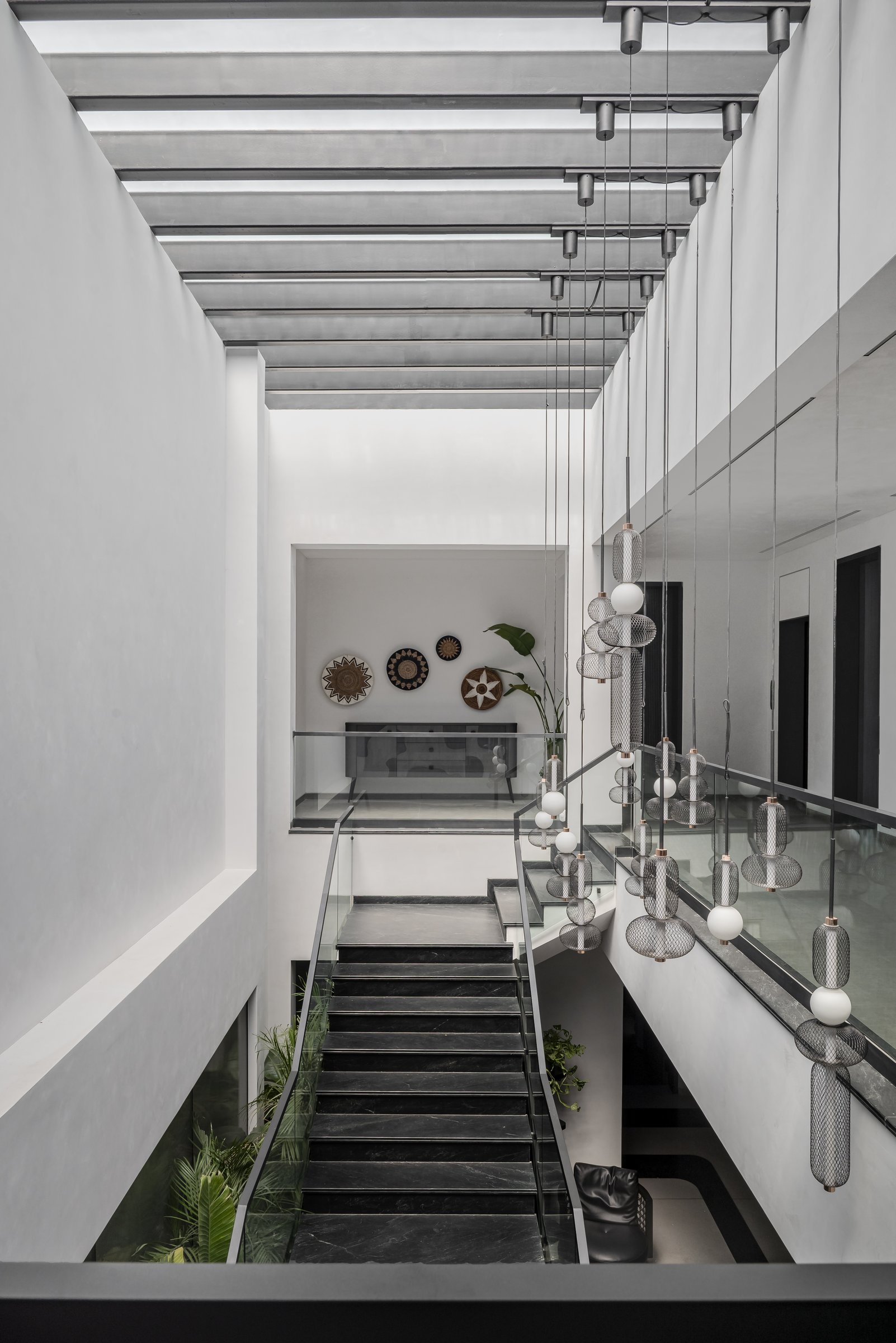 The double-height stair void hung with custom mesh-and-globe pendants by Agiyo