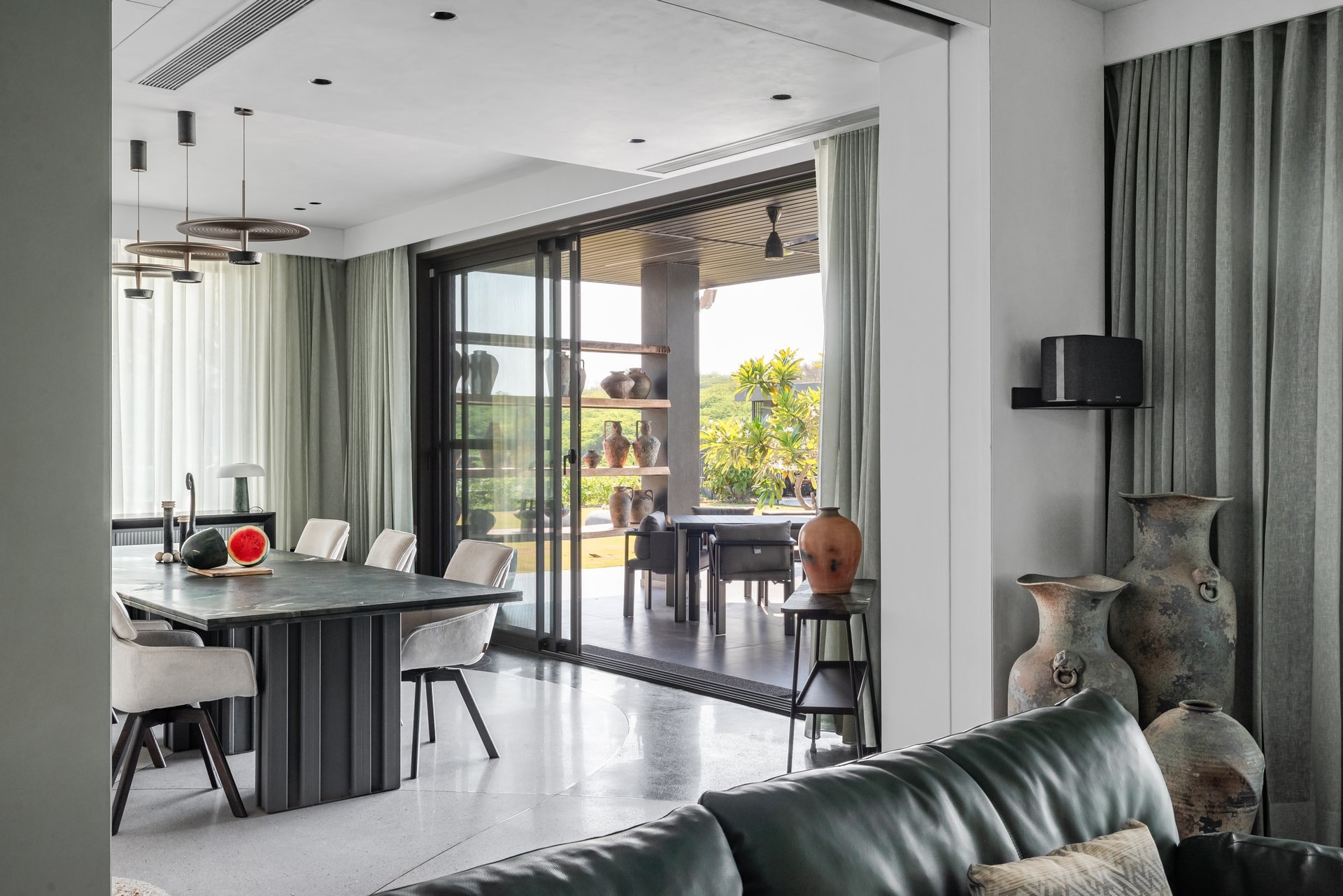 The dining zone flows from the living room, with weathered vessels marking the threshold to the outdoor terrace