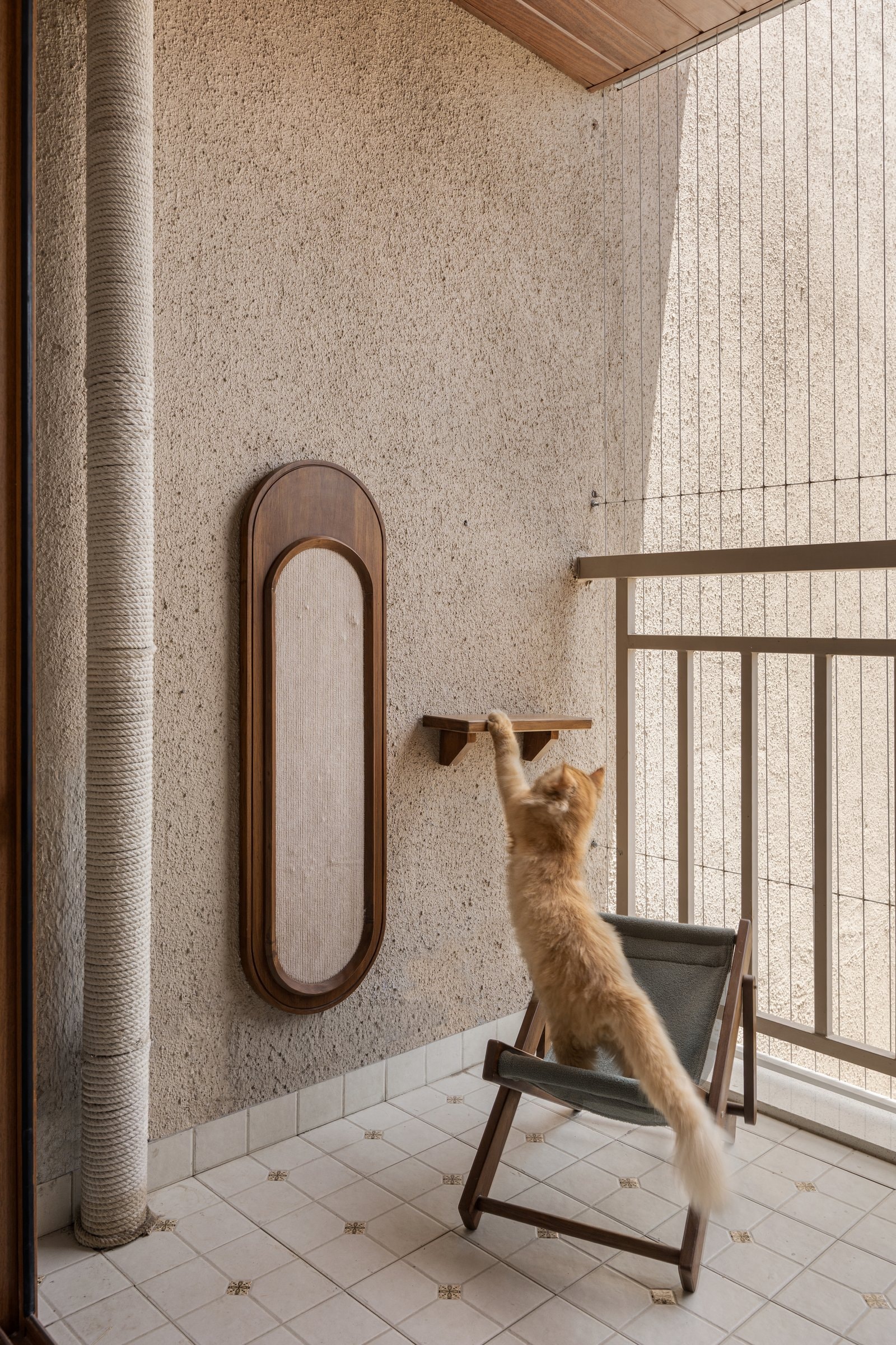 The balcony, reimagined as a cat play area: a rope-wrapped climbing column, a cantilevered timber ledge, and a framed scratch pad within a rounded surround