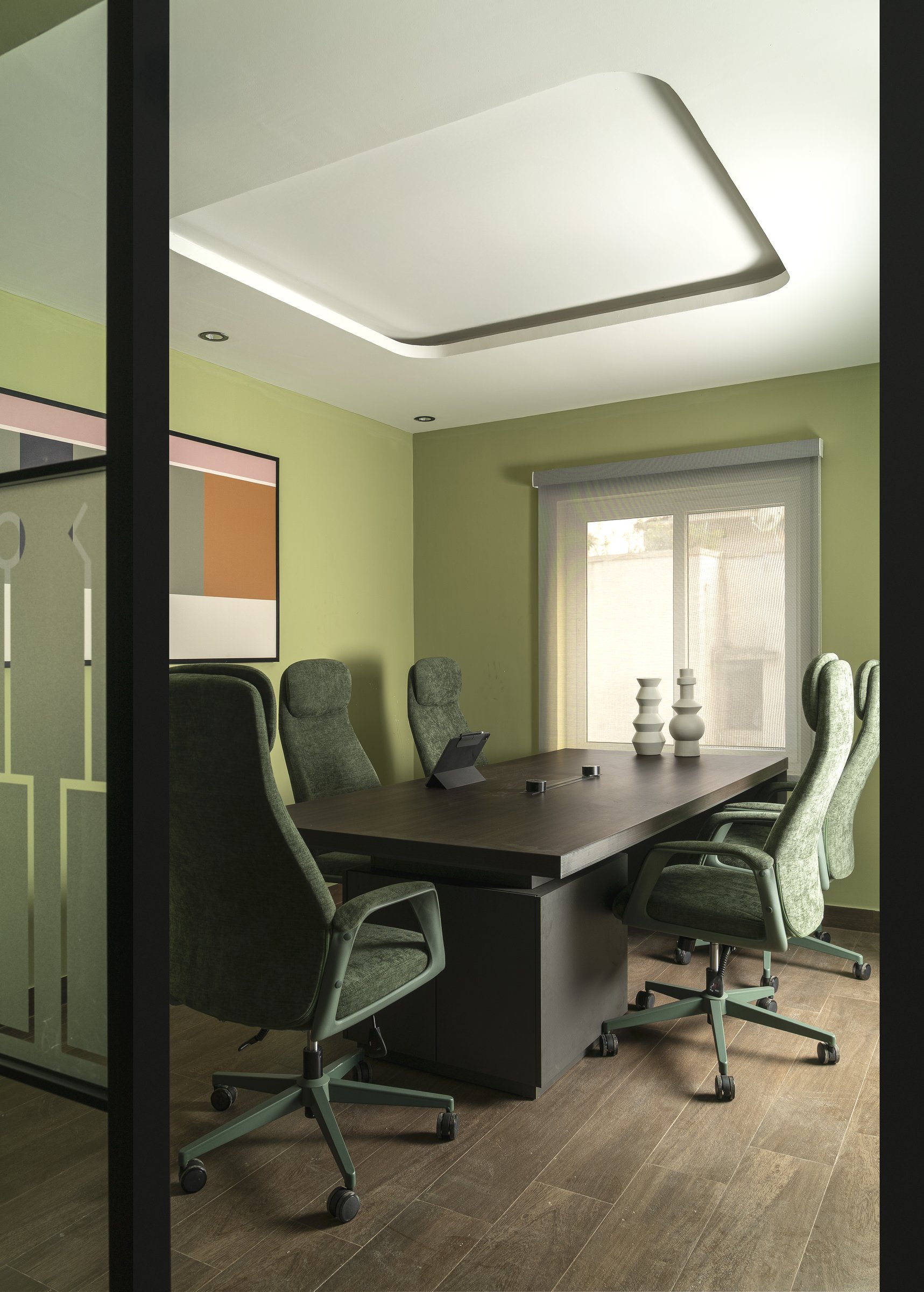 The meeting room, where mossy upholstery and a dark wood conference table give a quiet executive register