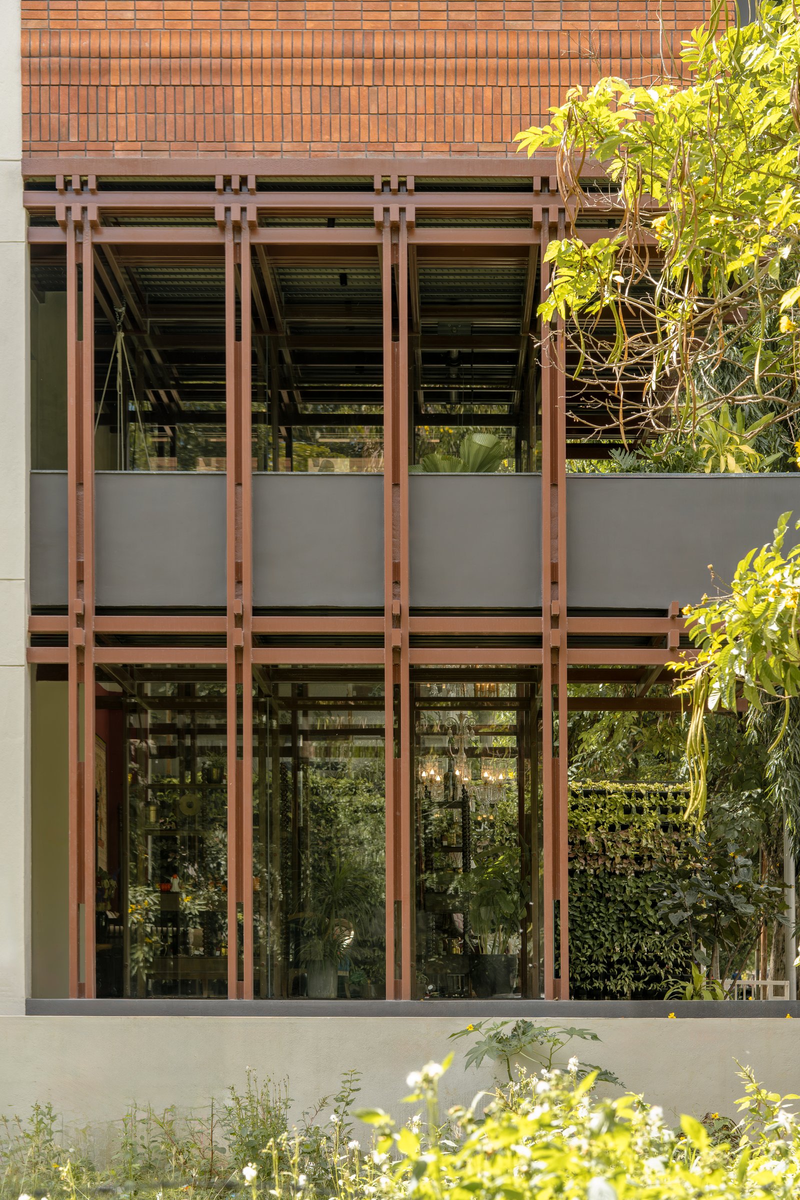 The paired-column steel grammar that supports the brick volume above, visible through the double-height glazing