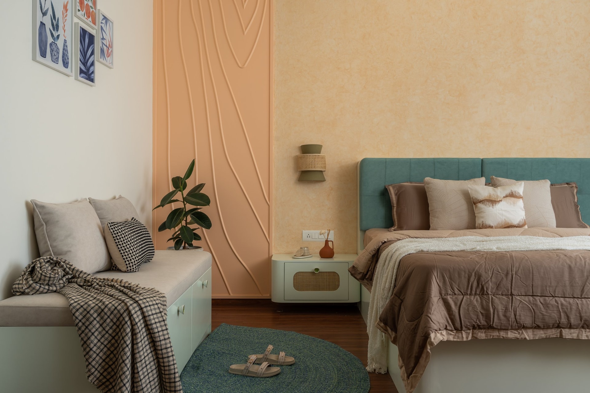 The master bedroom, where a sculpted peach relief panel sits beside a sand-toned textured wall and a teal upholstered headboard