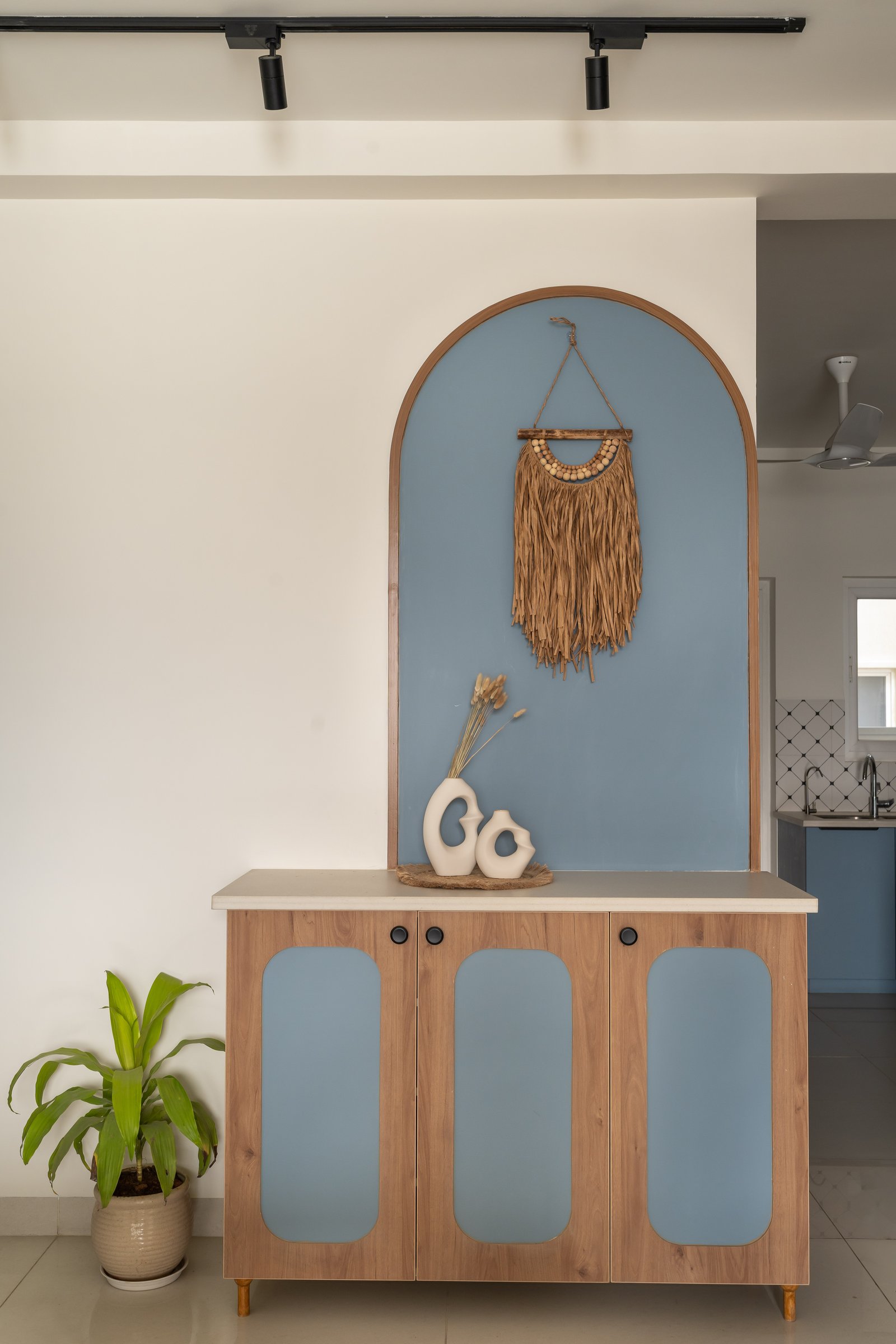 The foyer console: a walnut-toned cabinet with arched powder-blue inserts establishes the home's coastal-modern grammar