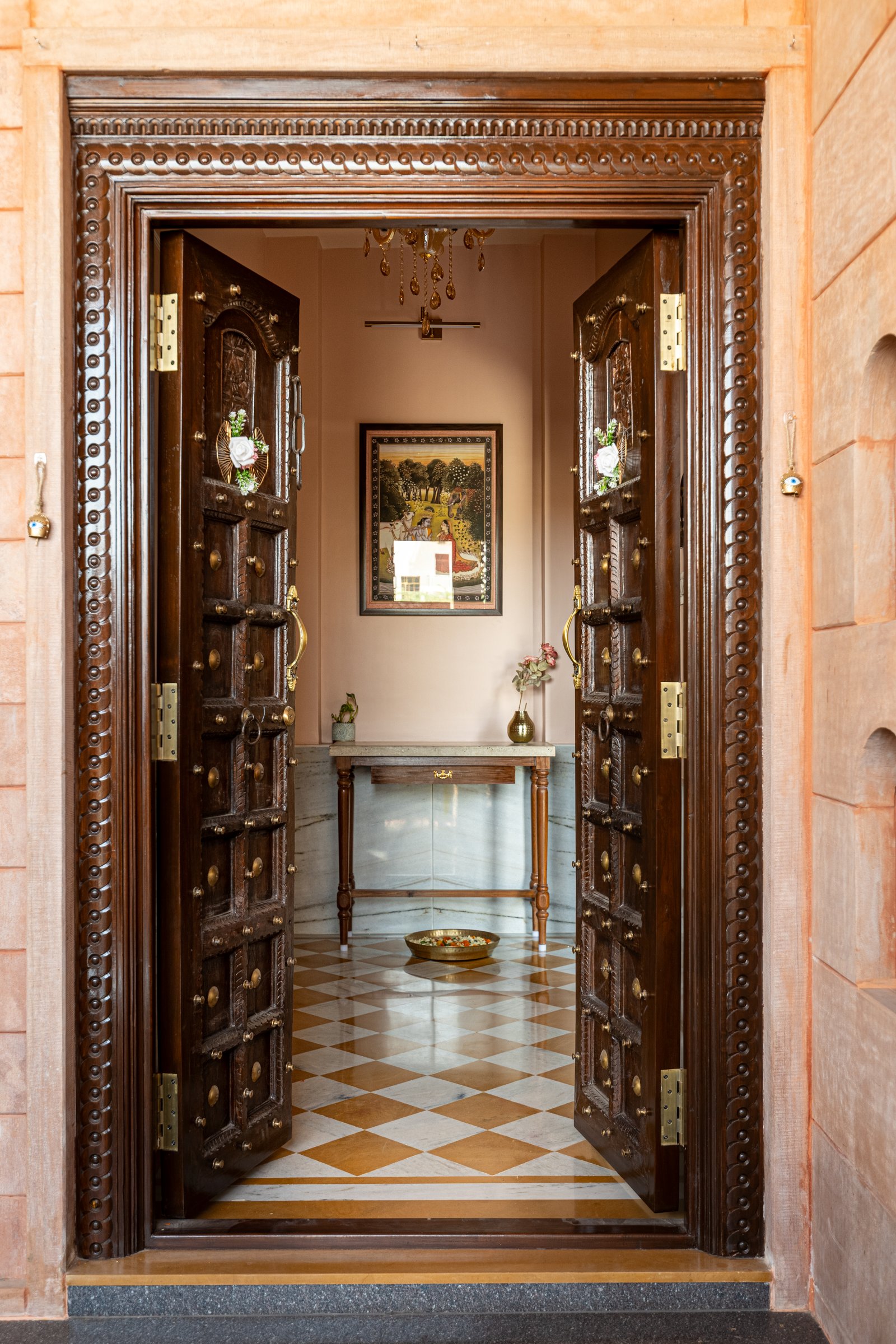 The entry: a restored heritage door in carved wood and brass studwork opens onto a checkerboard marble floor