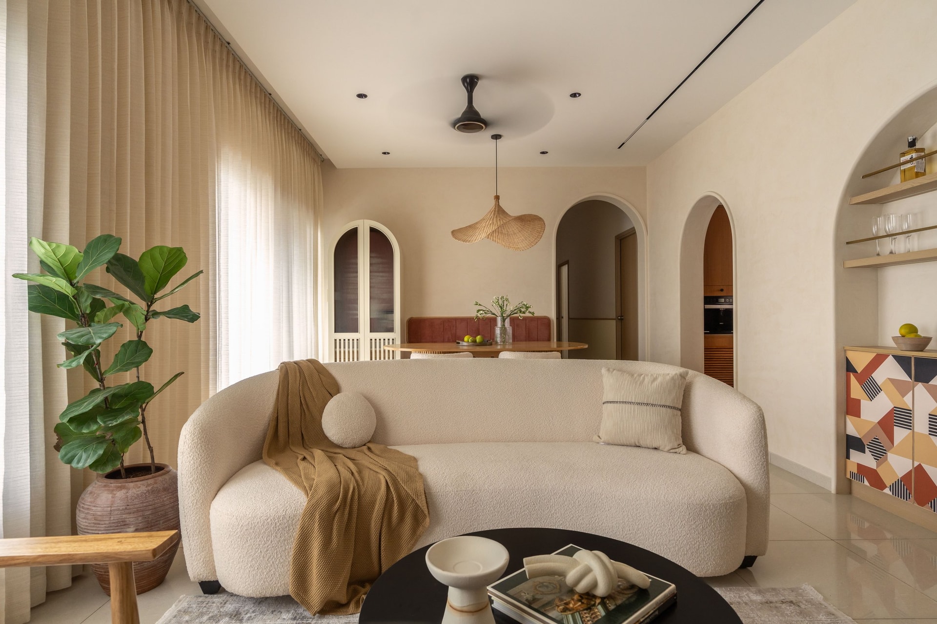 The curved boucle sofa, anchored by a black coffee table and a fiddle-leaf fig in terracotta
