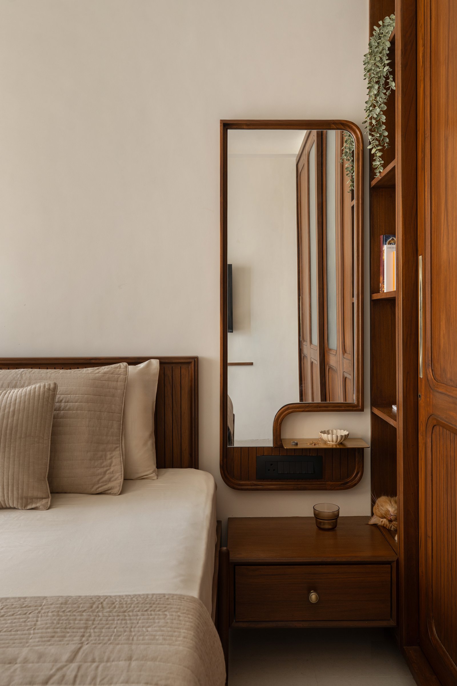 A rounded teak mirror and a brass utility tray turn a sliver of wall into a considered dressing moment