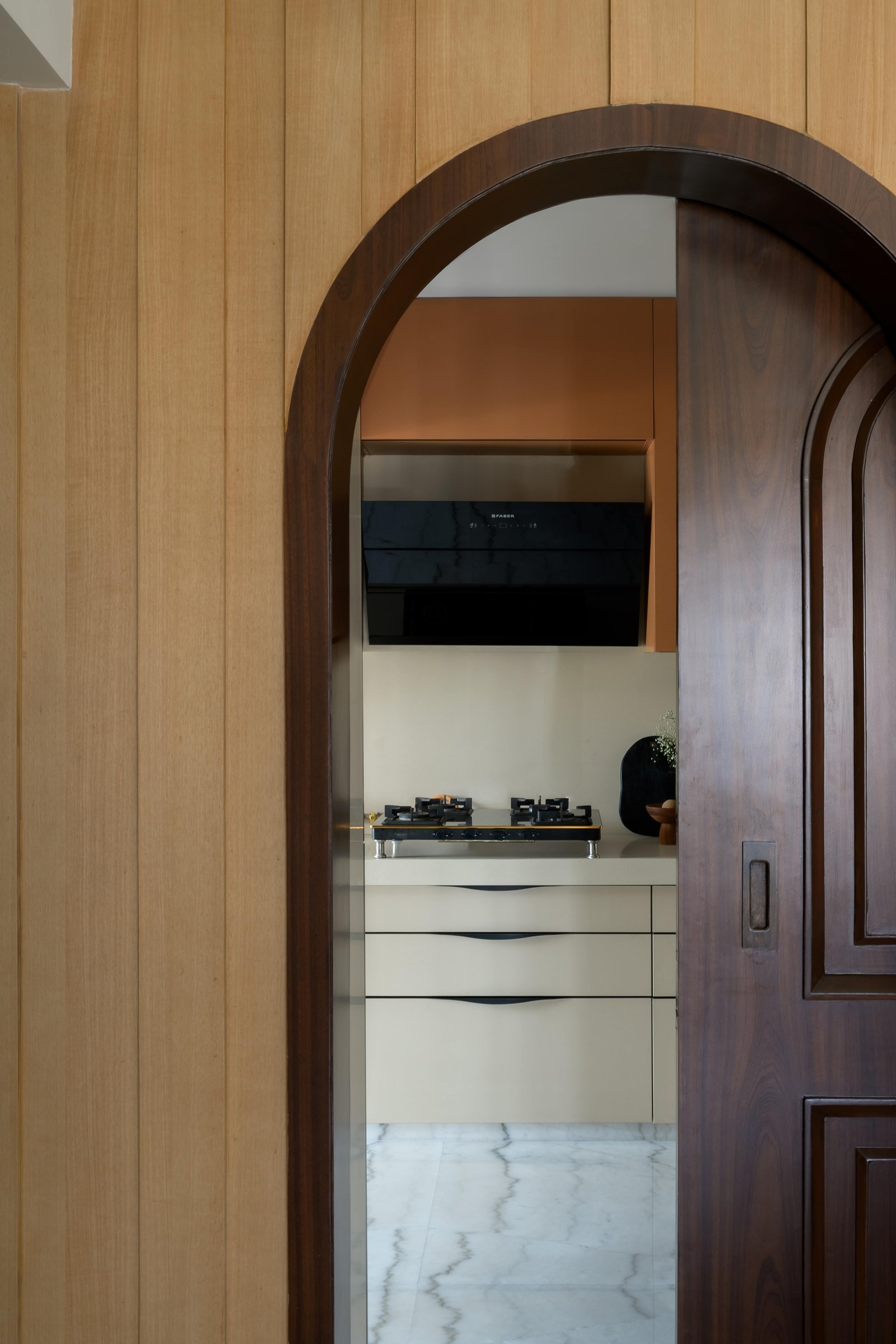 The arched panelled-wood threshold to the kitchen frames it like a still life
