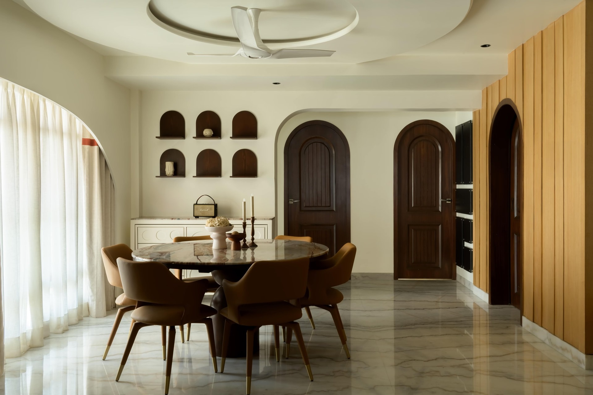 The dining room, anchored by a stone-topped round table beneath a circular ceiling cutout