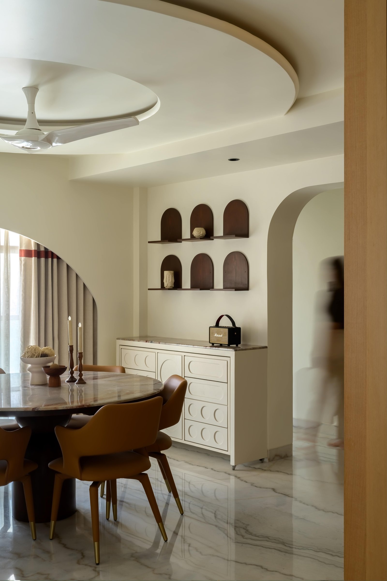 The credenza echoes the arch language of the niche wall above it