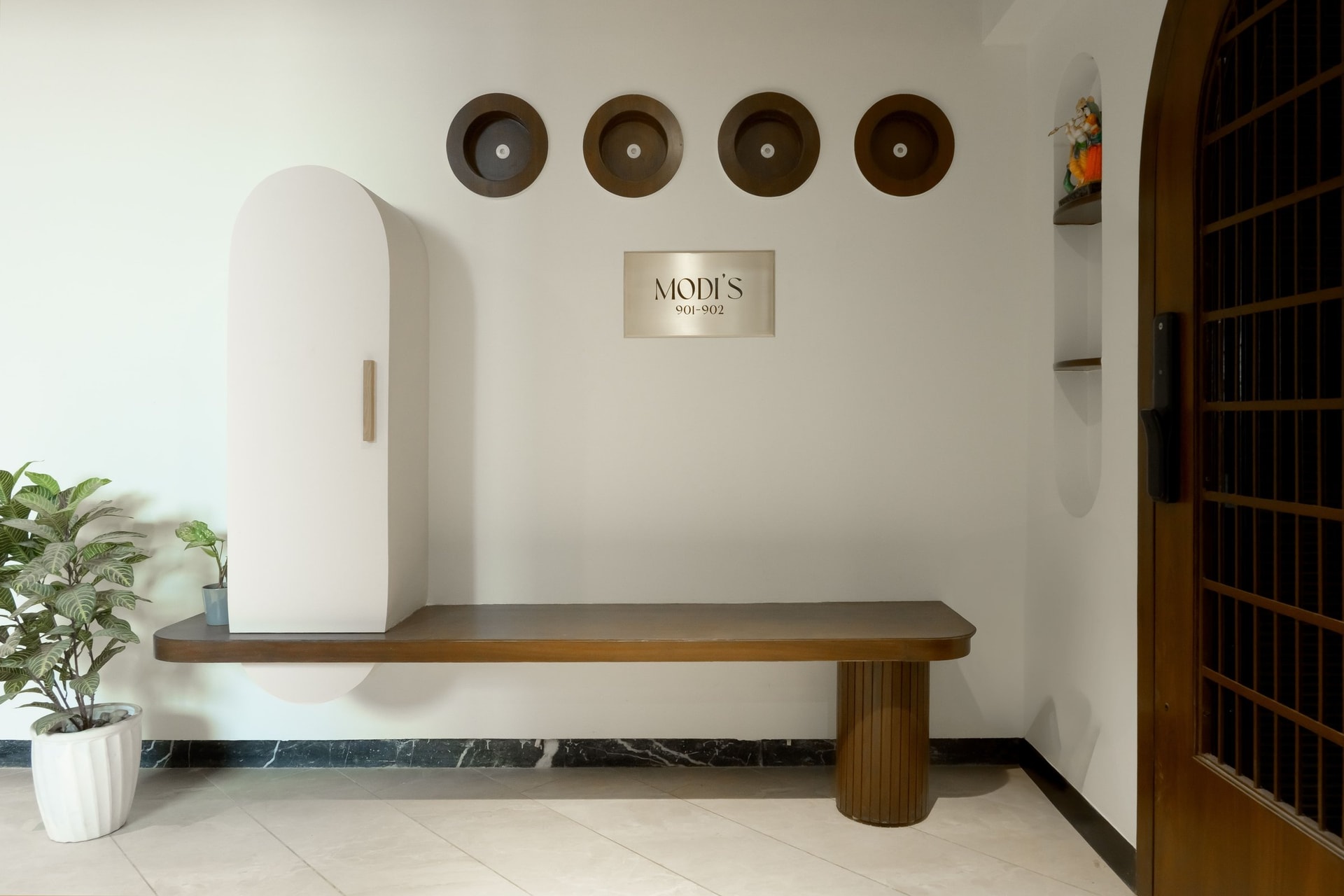 The arrival landing: a floating bench and four circular niches set the home's measured tone before the threshold is crossed