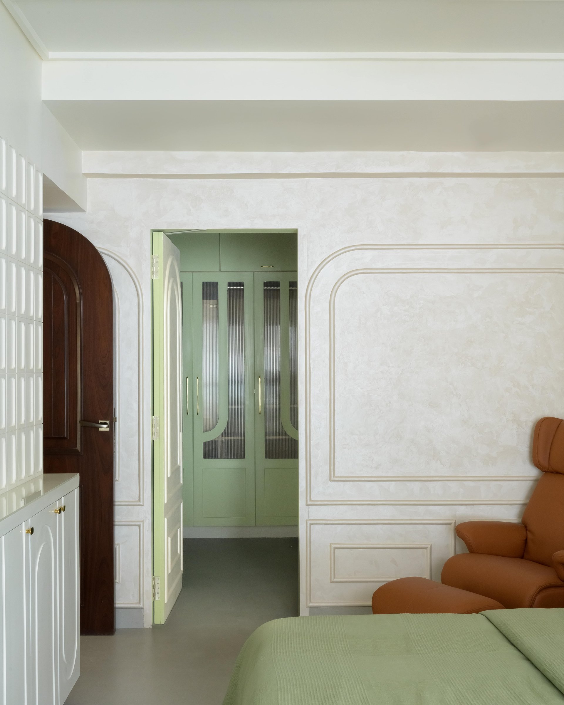 A sage-green dressing area glimpsed through the master bedroom's open doorway