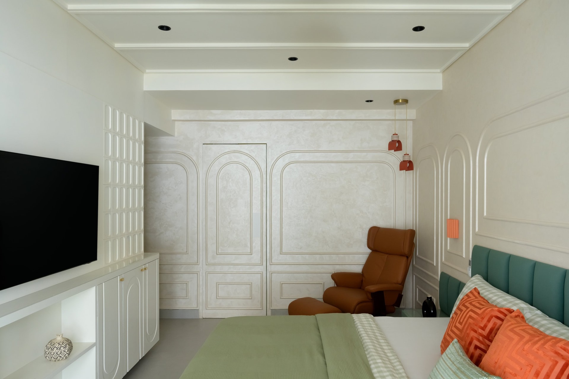 The master bedroom, where moulded plaster walls meet a teal headboard and coral pendants