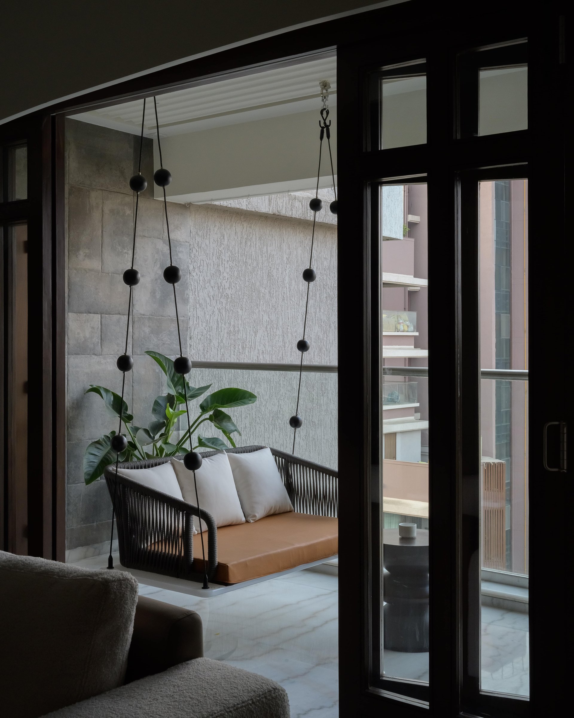 The balcony, with its rope-strung swing seat against textured grey stone
