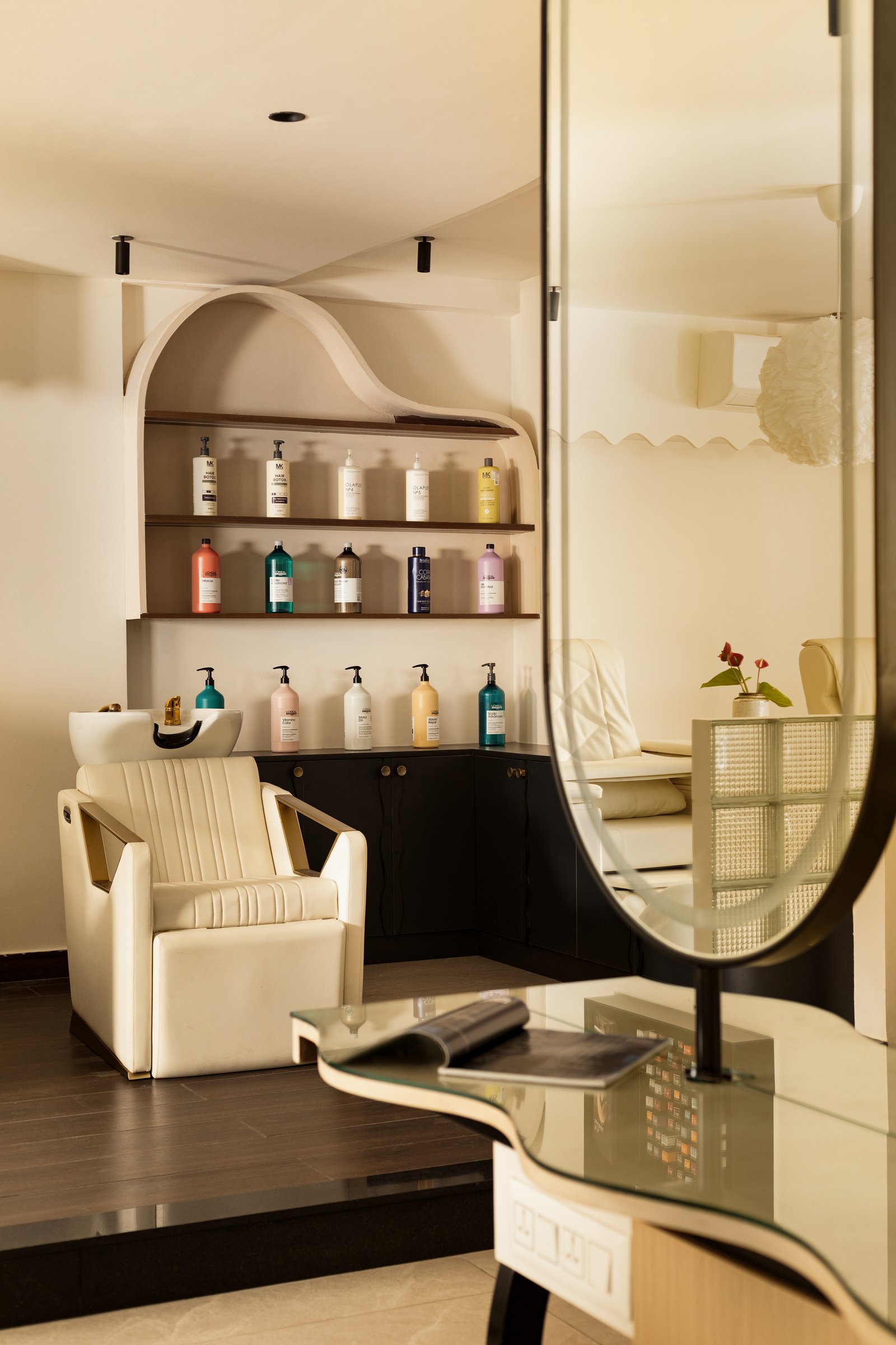 The wash zone: an arched niche of haircare product set against black cabinetry and a glass-block partition