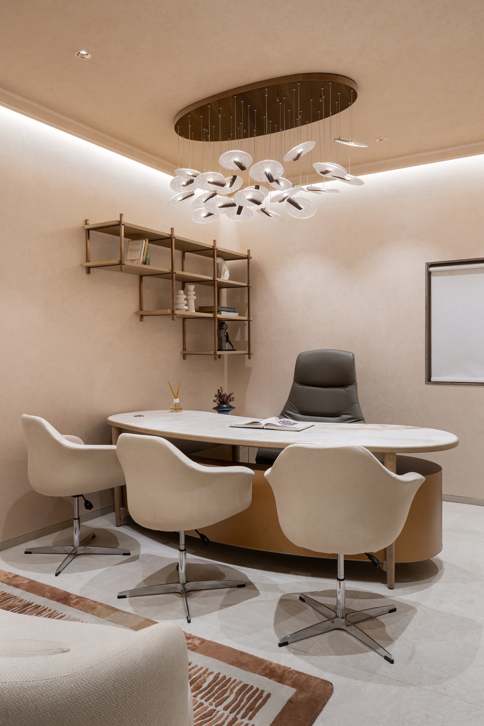 The director's cabin allows itself a single piece of theatre: a suspended cluster of glass discs above a stone-topped desk