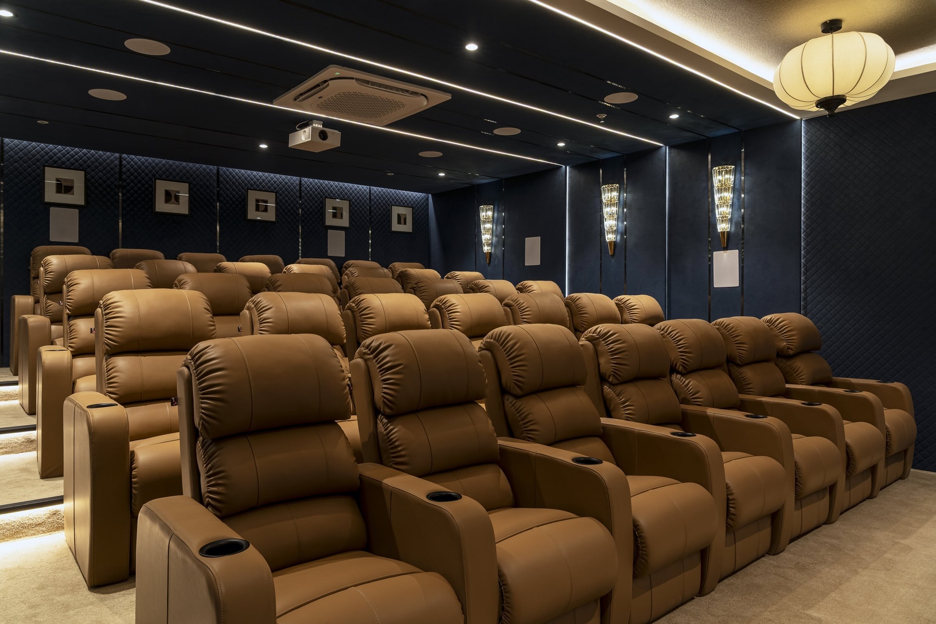 The mini theatre: midnight blue quilted walls and disciplined rows of tan recliners