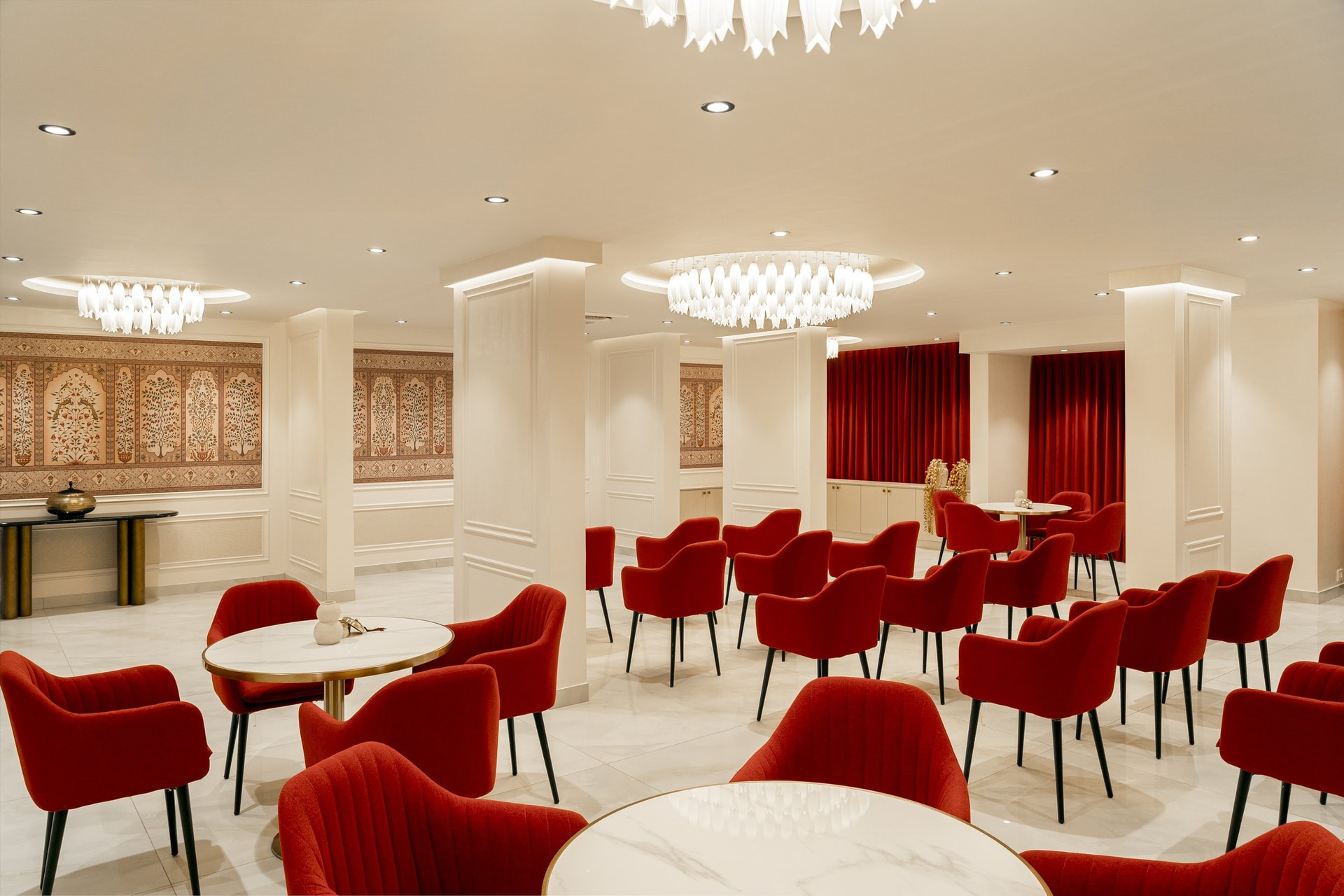 The multipurpose hall, where red velvet armchairs face a panelled mural of stylised flowering trees