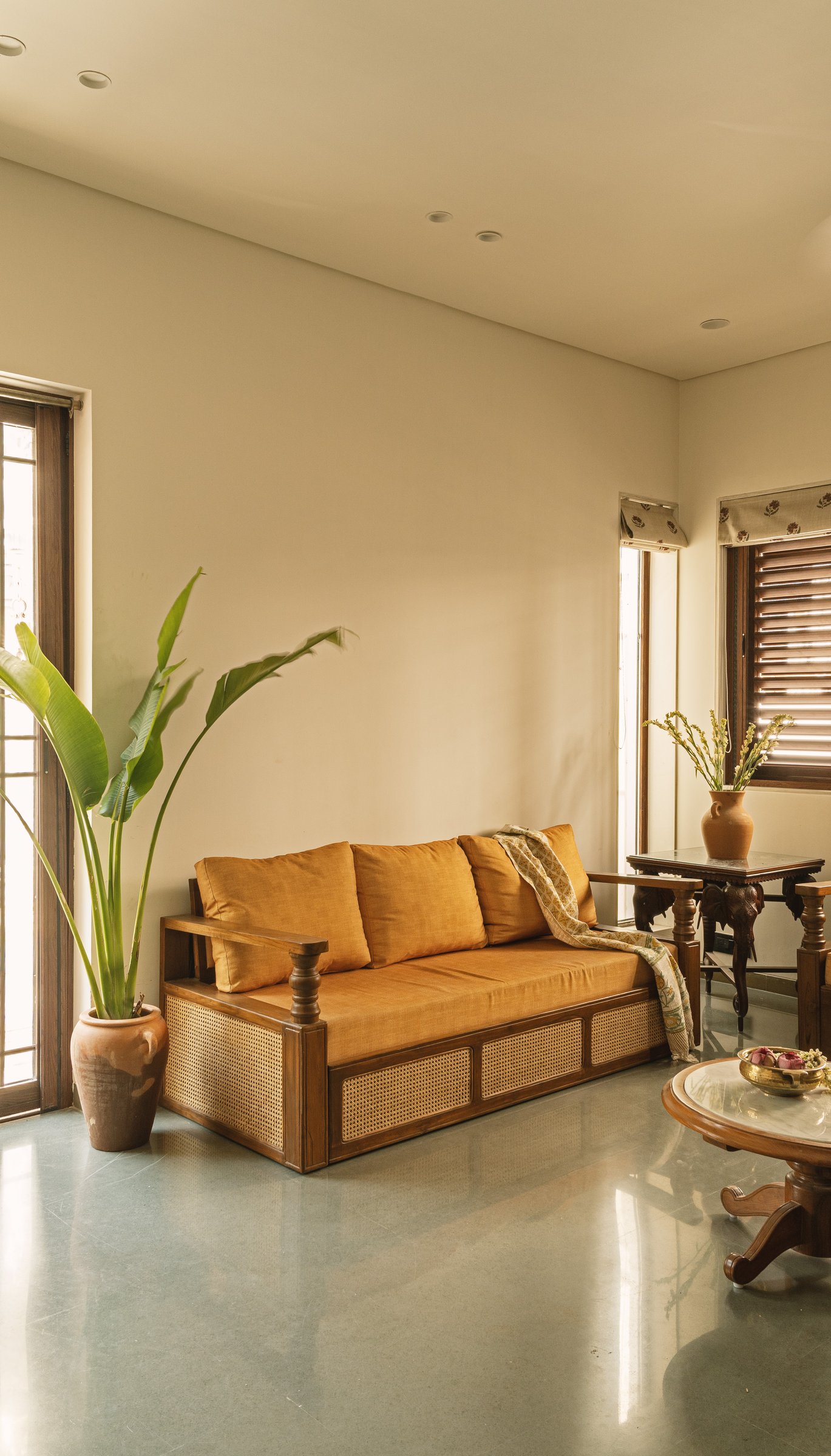 The living room daybed in cane and wood, its mustard cushions striking the home's clearest chord of colour