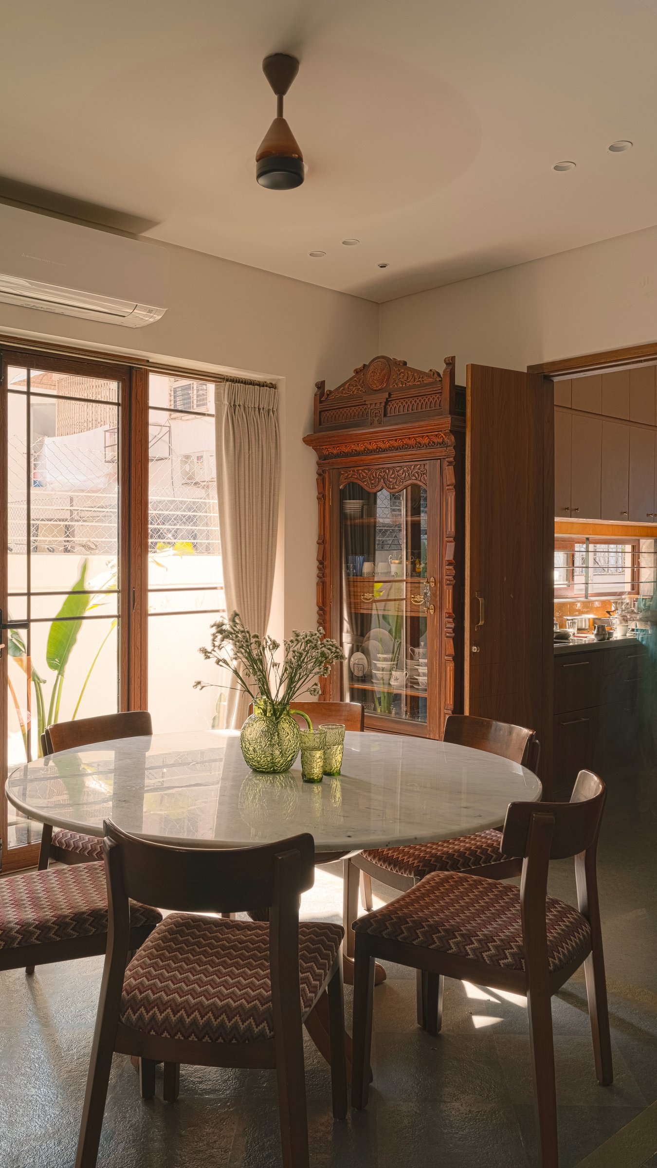 The heirloom carved cabinet stands beside the kitchen doorway, the modern joinery stepping back to let it speak