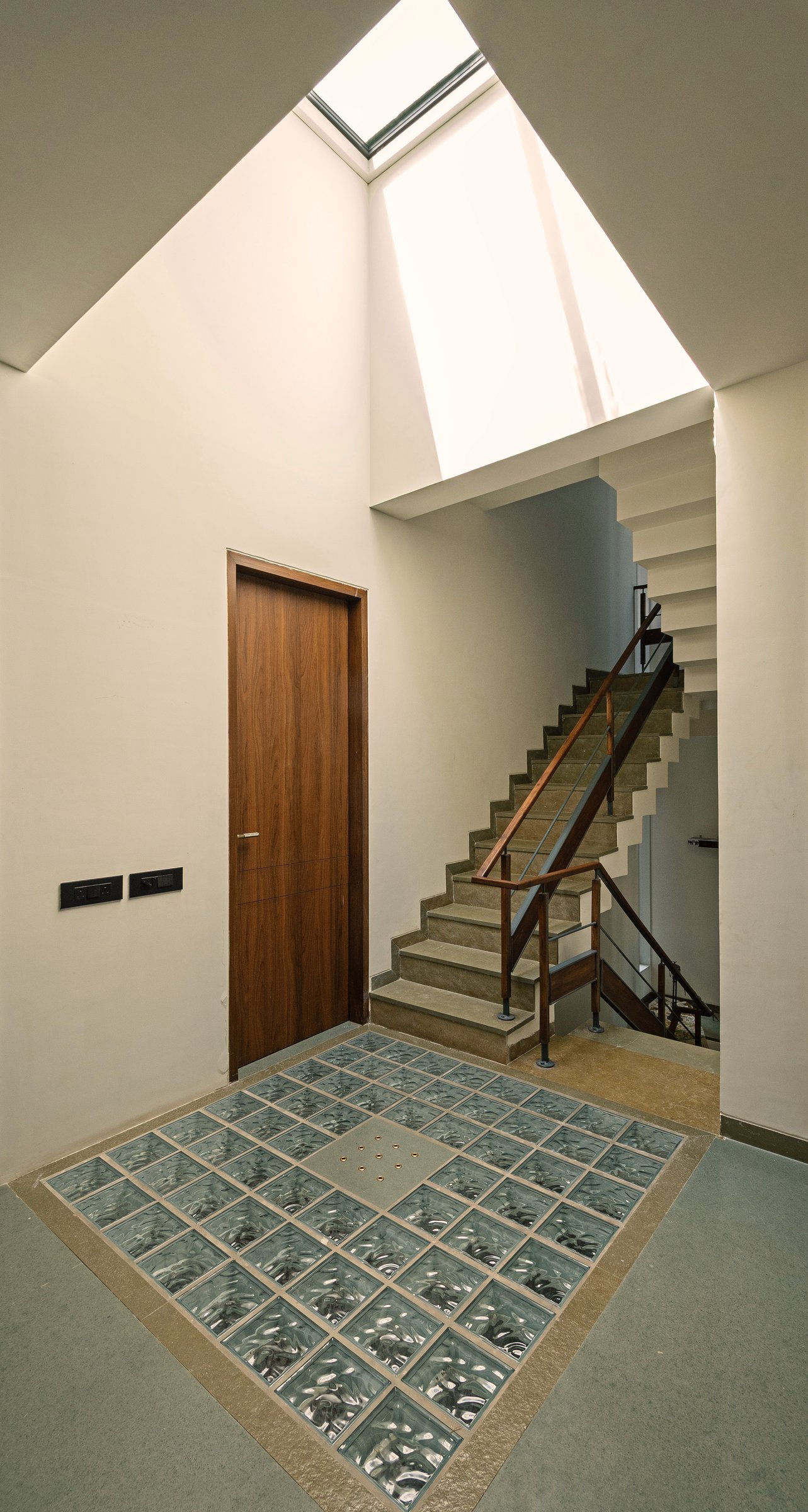 The internal stair: a skylight cuts a pyramid of light above, glass-block flooring carries it down to the landing