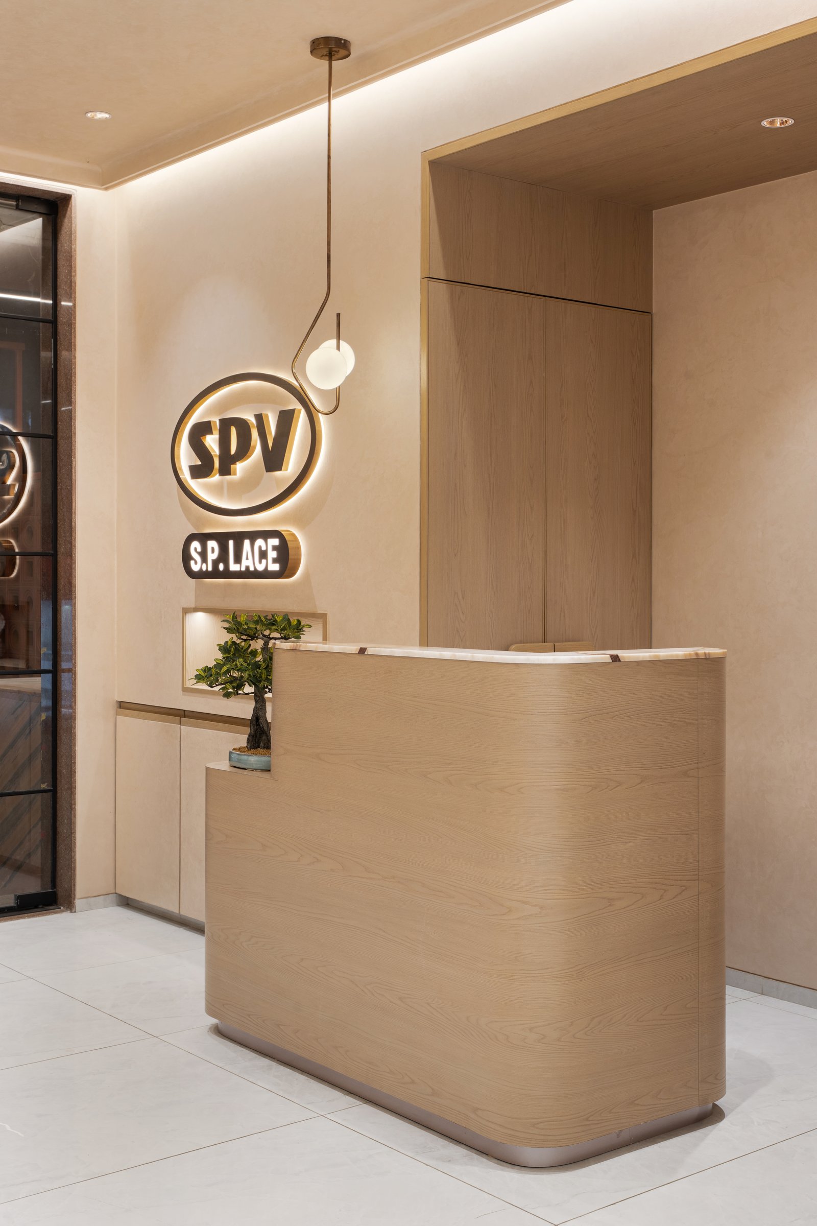 The reception, where a curved blond-wood counter and a single slim pendant set the tonal grammar of the whole project